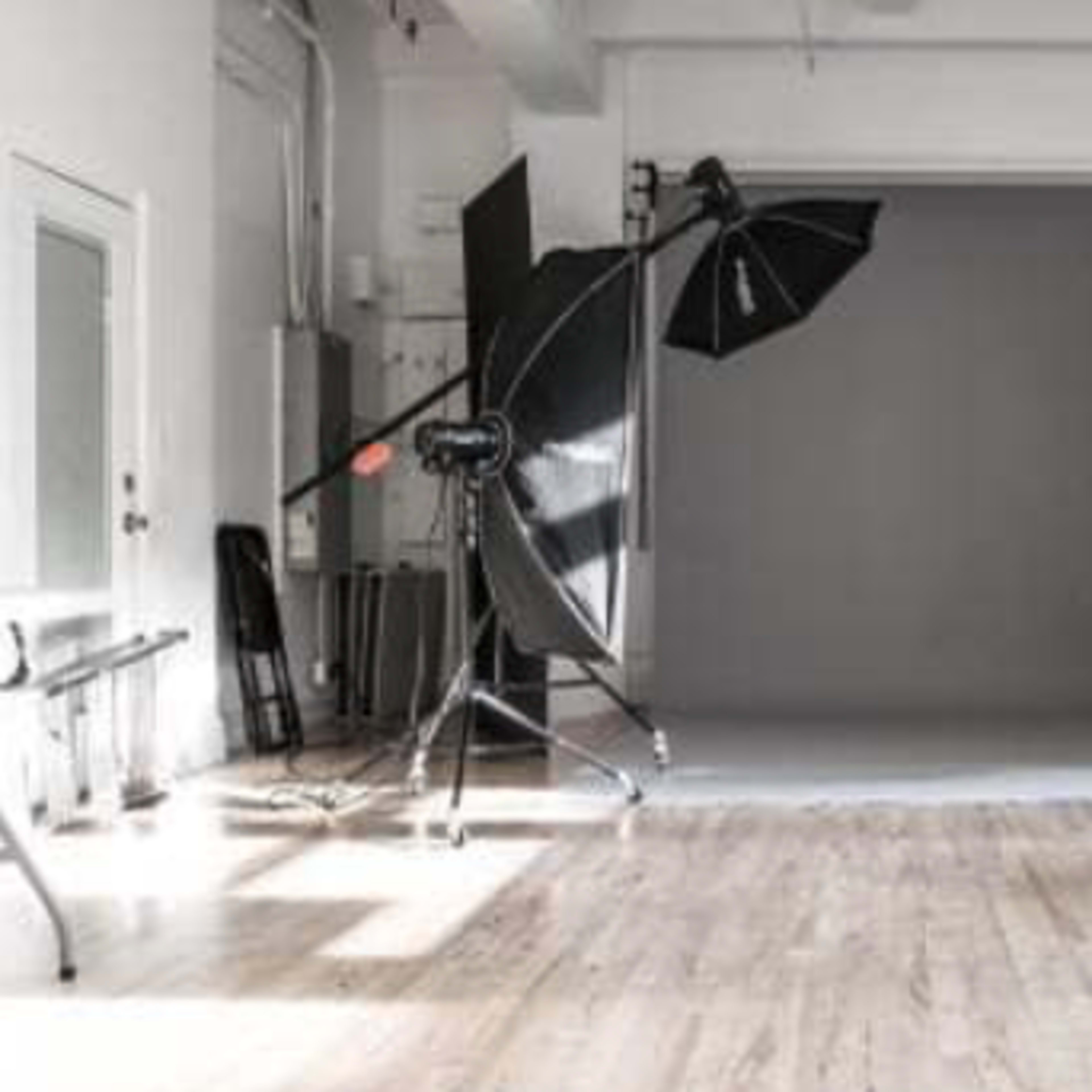 A photography studio equipped with lighting equipment, a backdrop, and preparation areas.