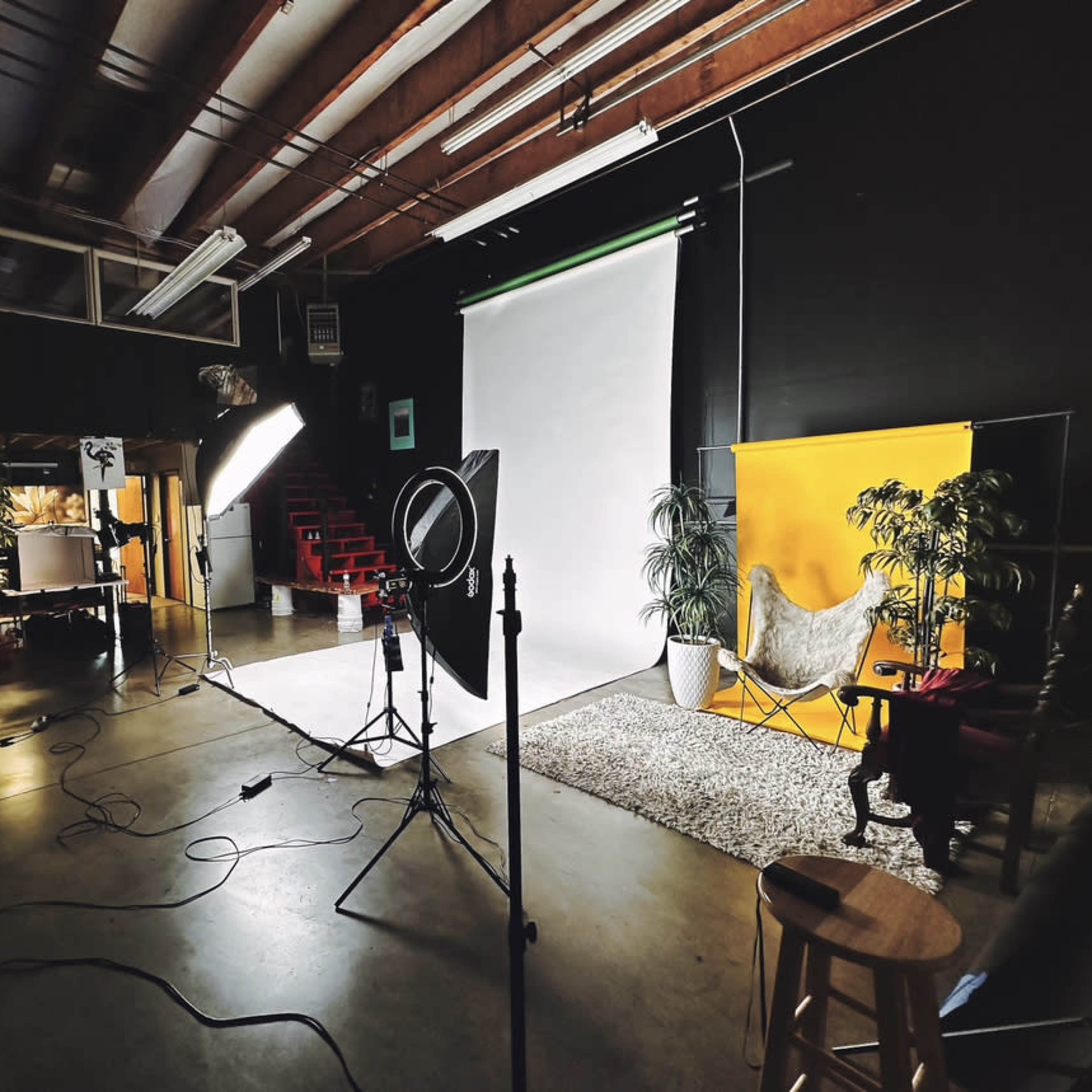 A photography studio setup with a backdrop, lighting equipment, and various props arranged for a photoshoot.