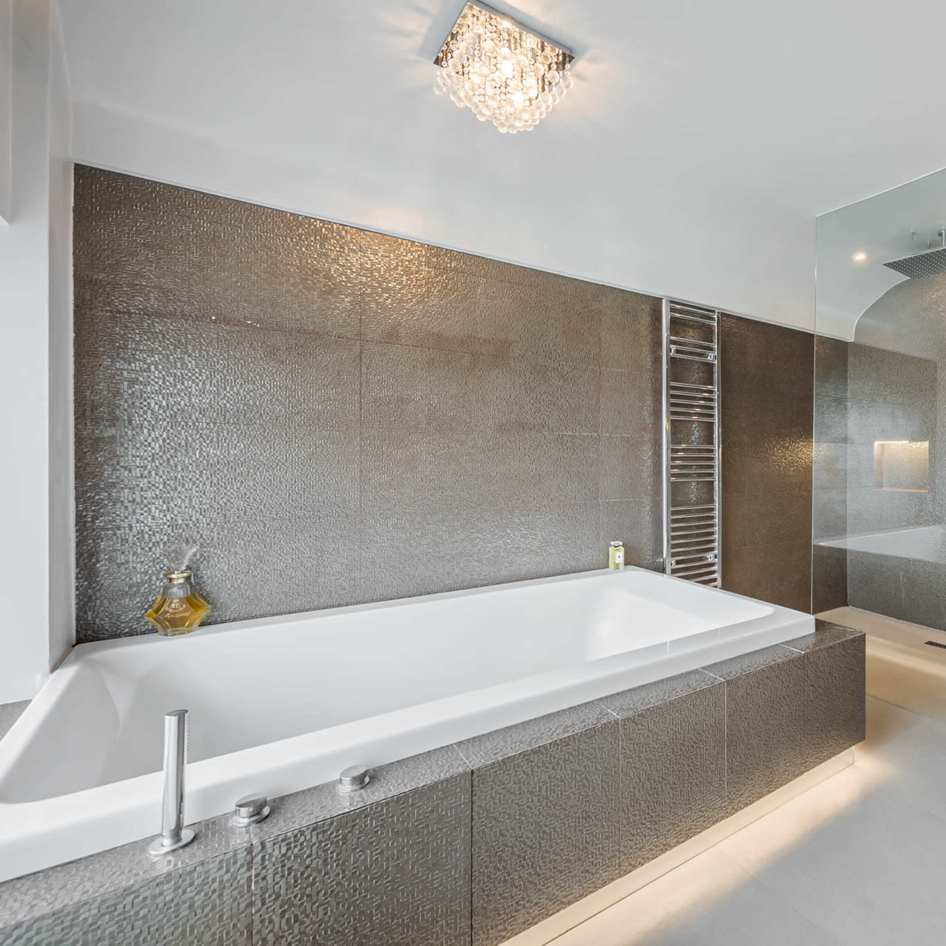 A modern bathroom featuring a freestanding bathtub, a glass shower enclosure, and textured wall panels.