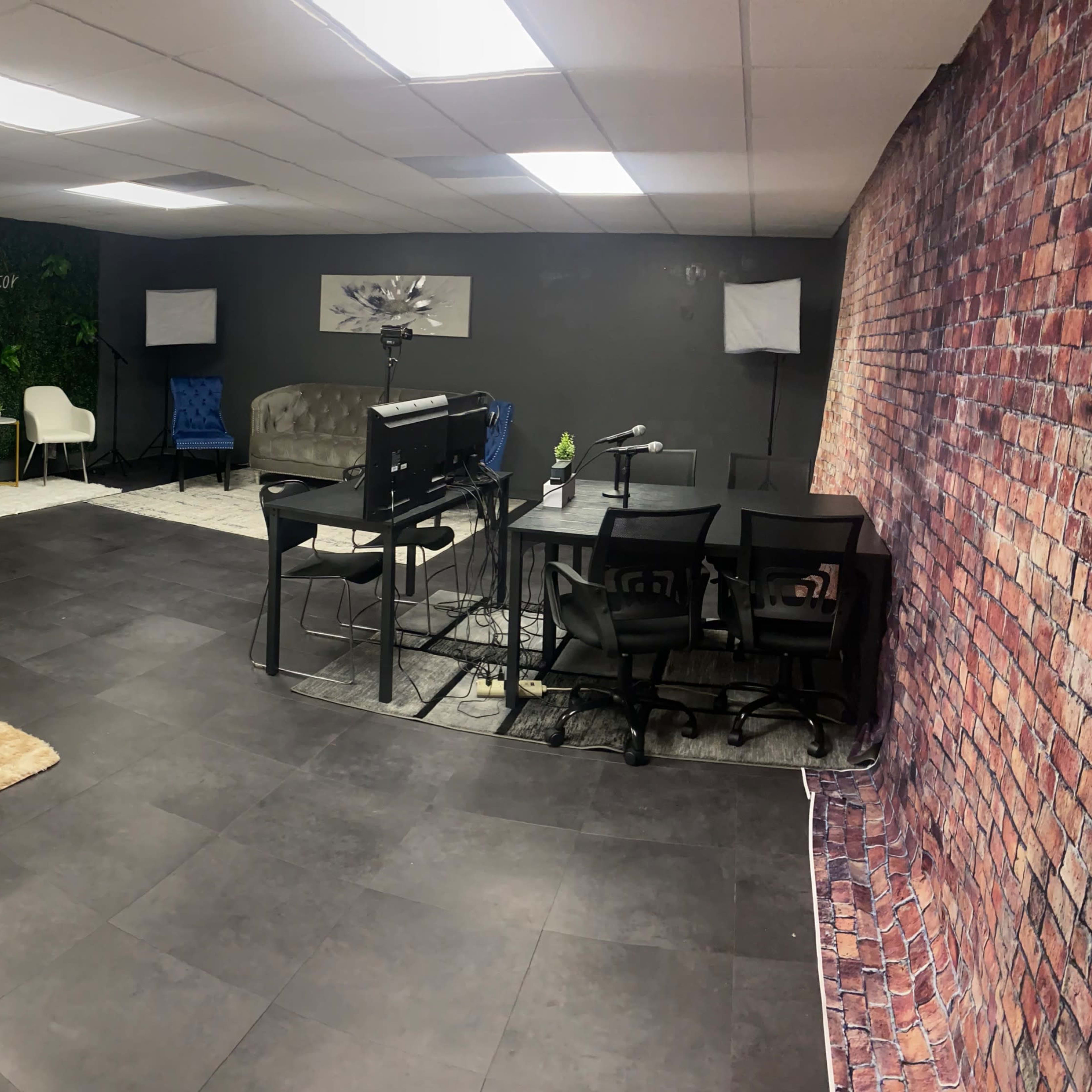 A modern office space featuring a mix of seating areas, a desk, and a wall with a brick design.
