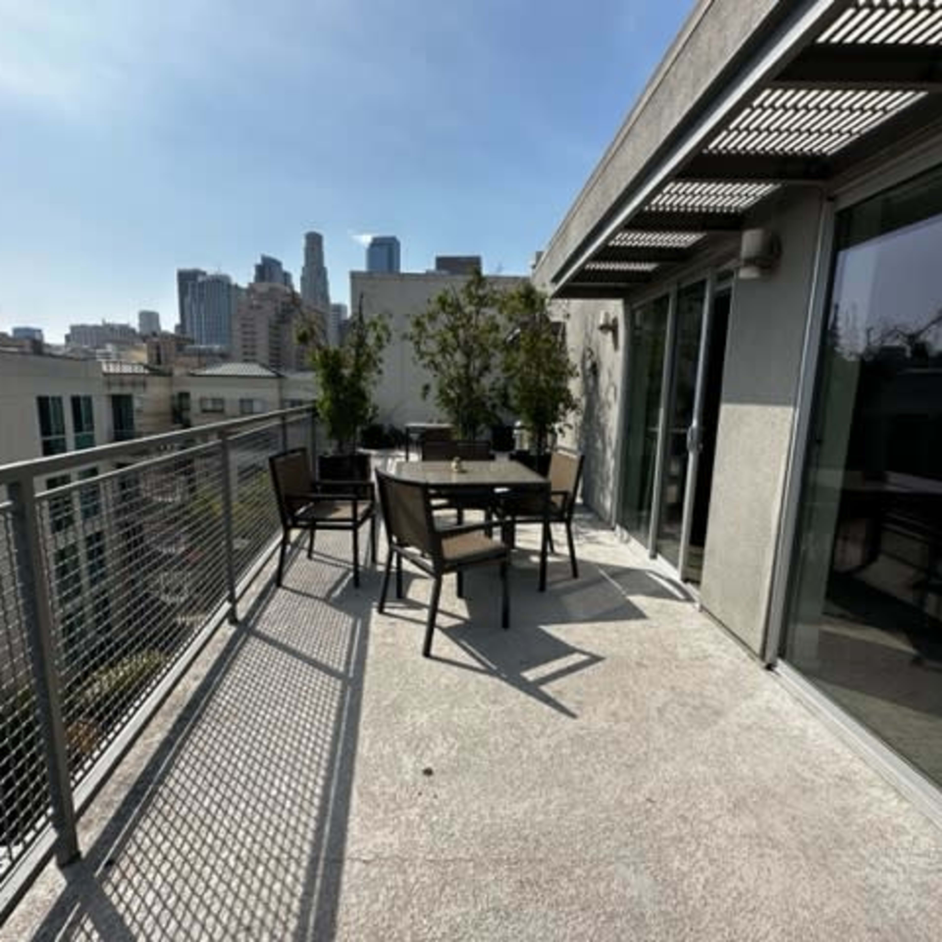A rooftop terrace with outdoor seating and a view of city skyscrapers in the background.