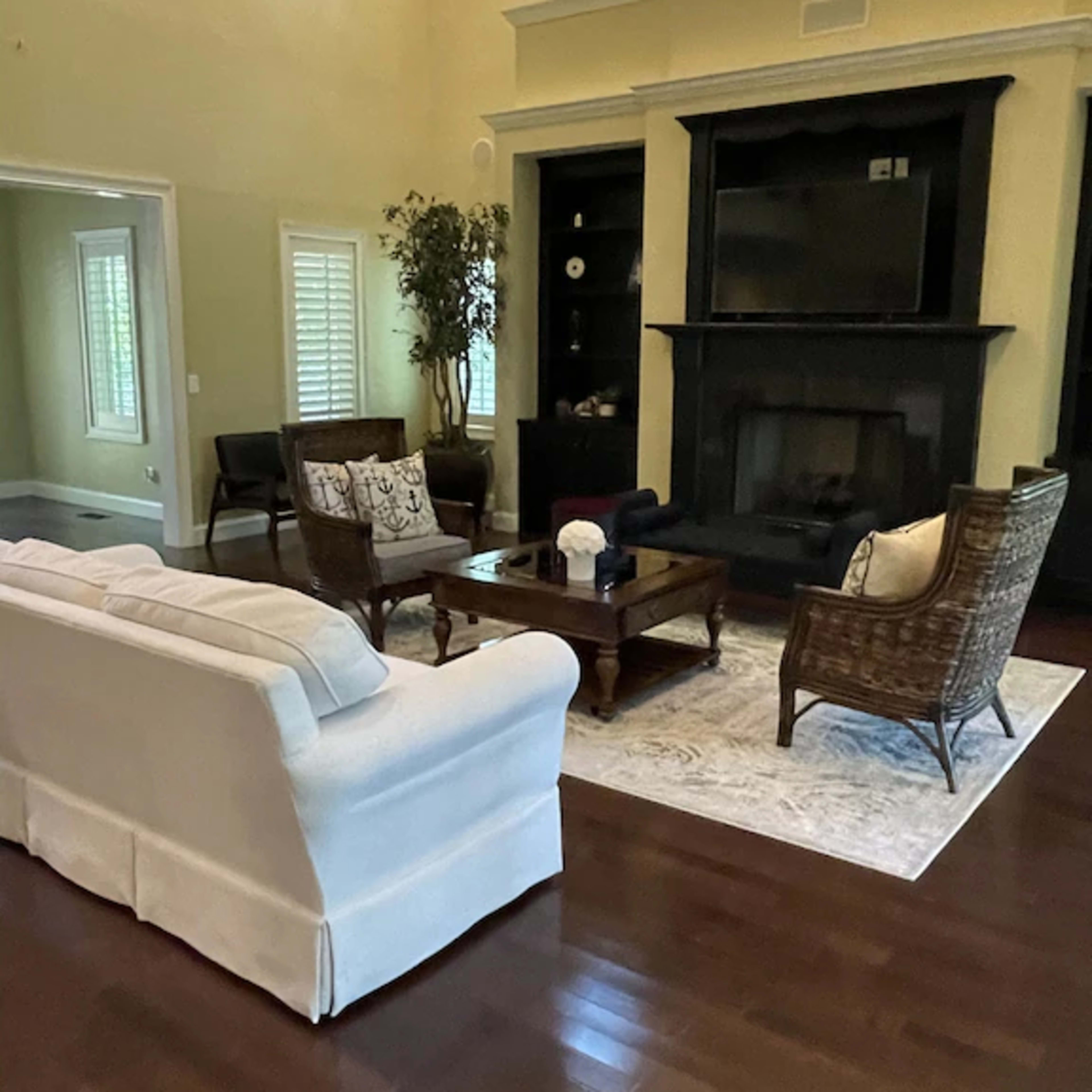 A spacious living room with a light-colored sofa, dark wooden furniture, and a fireplace.