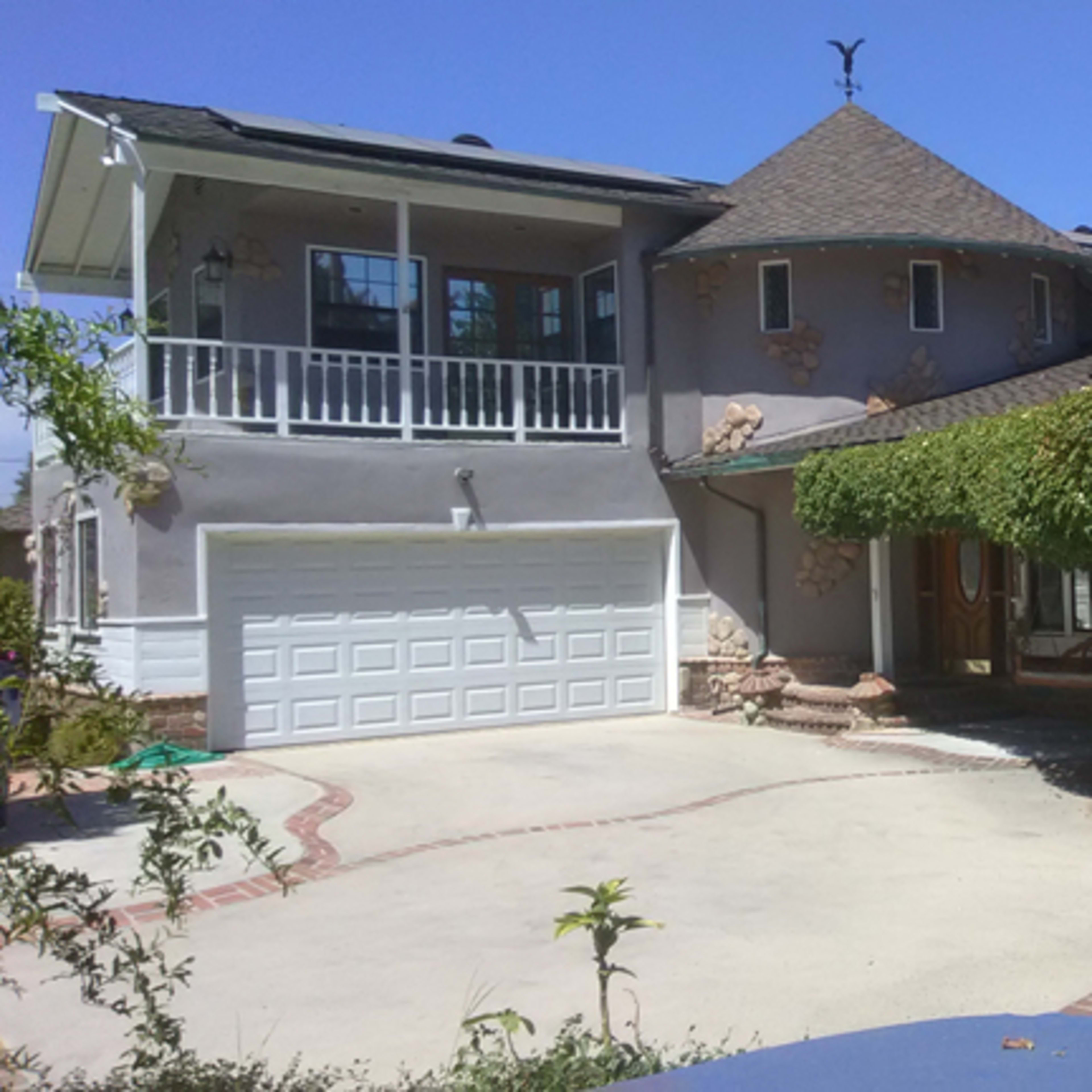 A unique house with a round turret, a two-car garage, and a driveway lined with brick patterns.