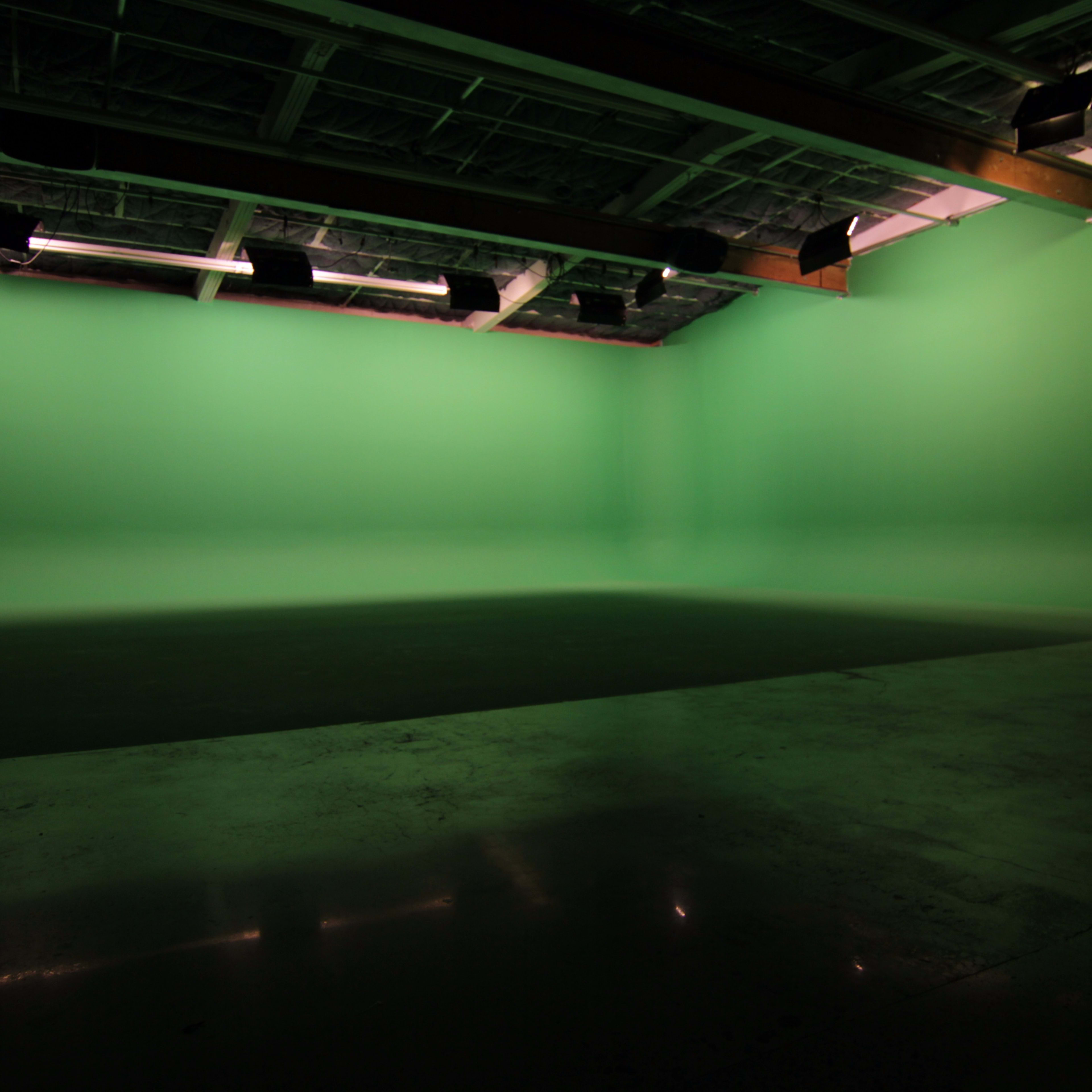 A large studio space with a bright green backdrop and a polished floor.