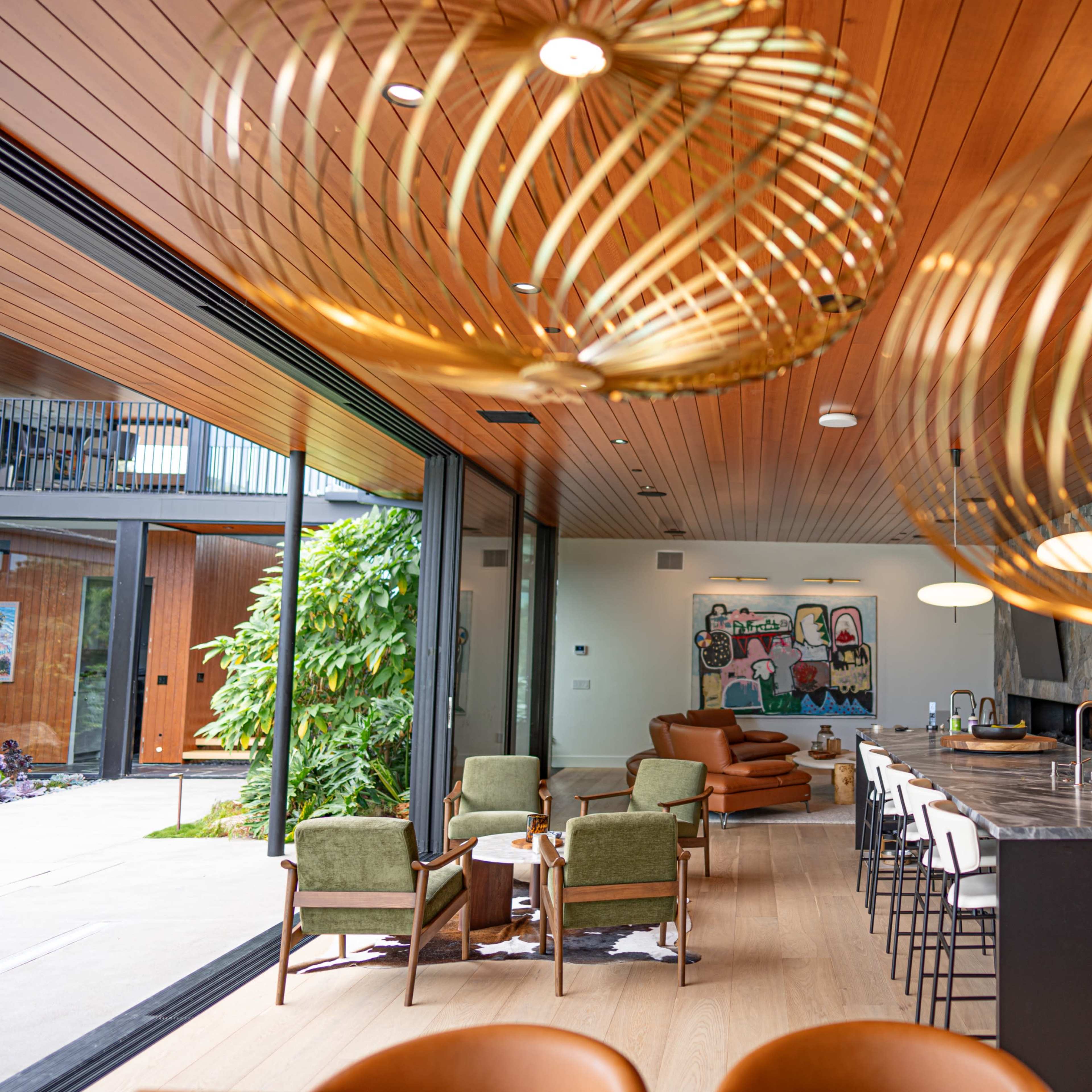 A modern kitchen and living area with wooden ceilings, large windows, and stylish seating arrangements.