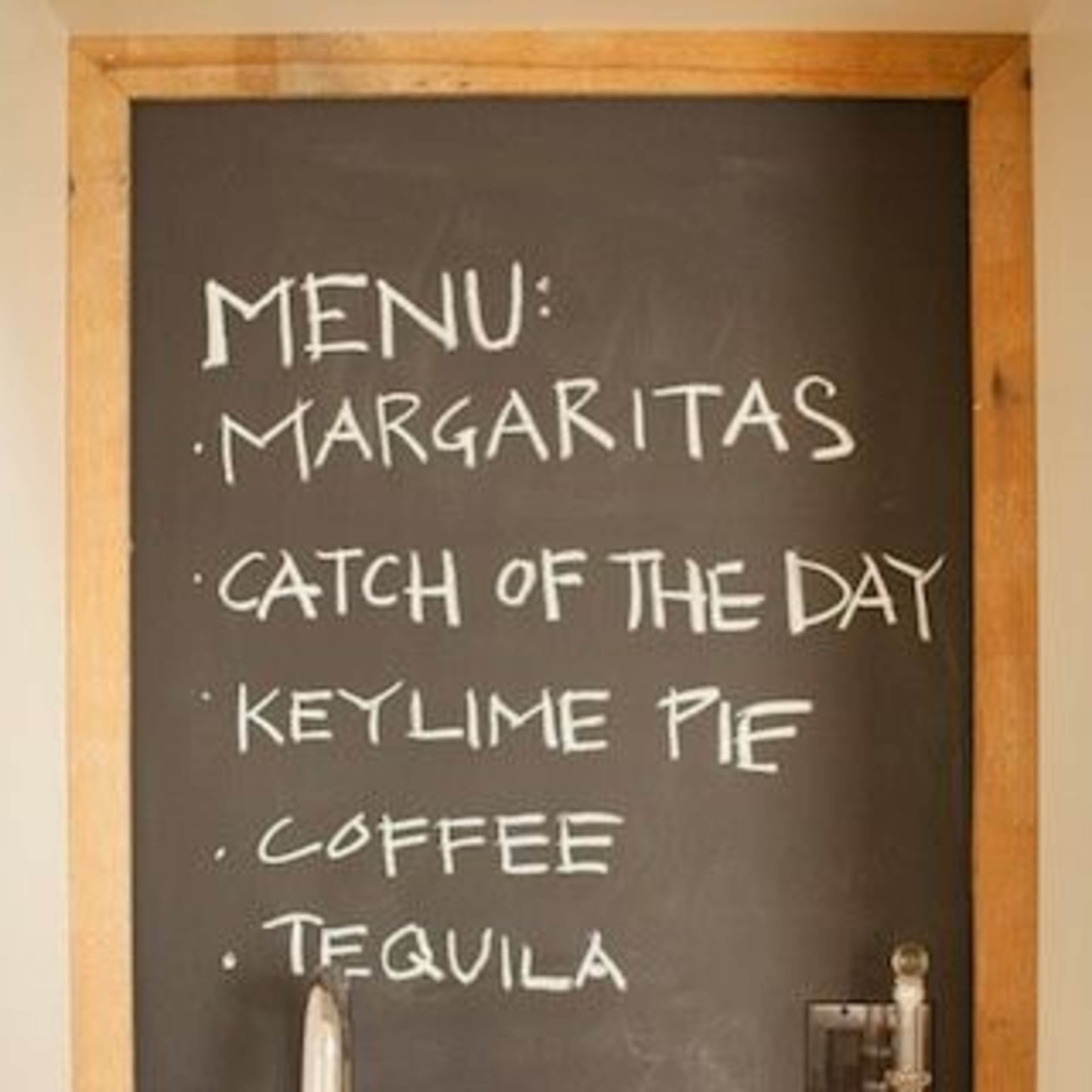 A chalkboard menu displays "Margaritas," "Catch of the Day," "Key Lime Pie," "Coffee," and "Tequila" in a kitchen setting.