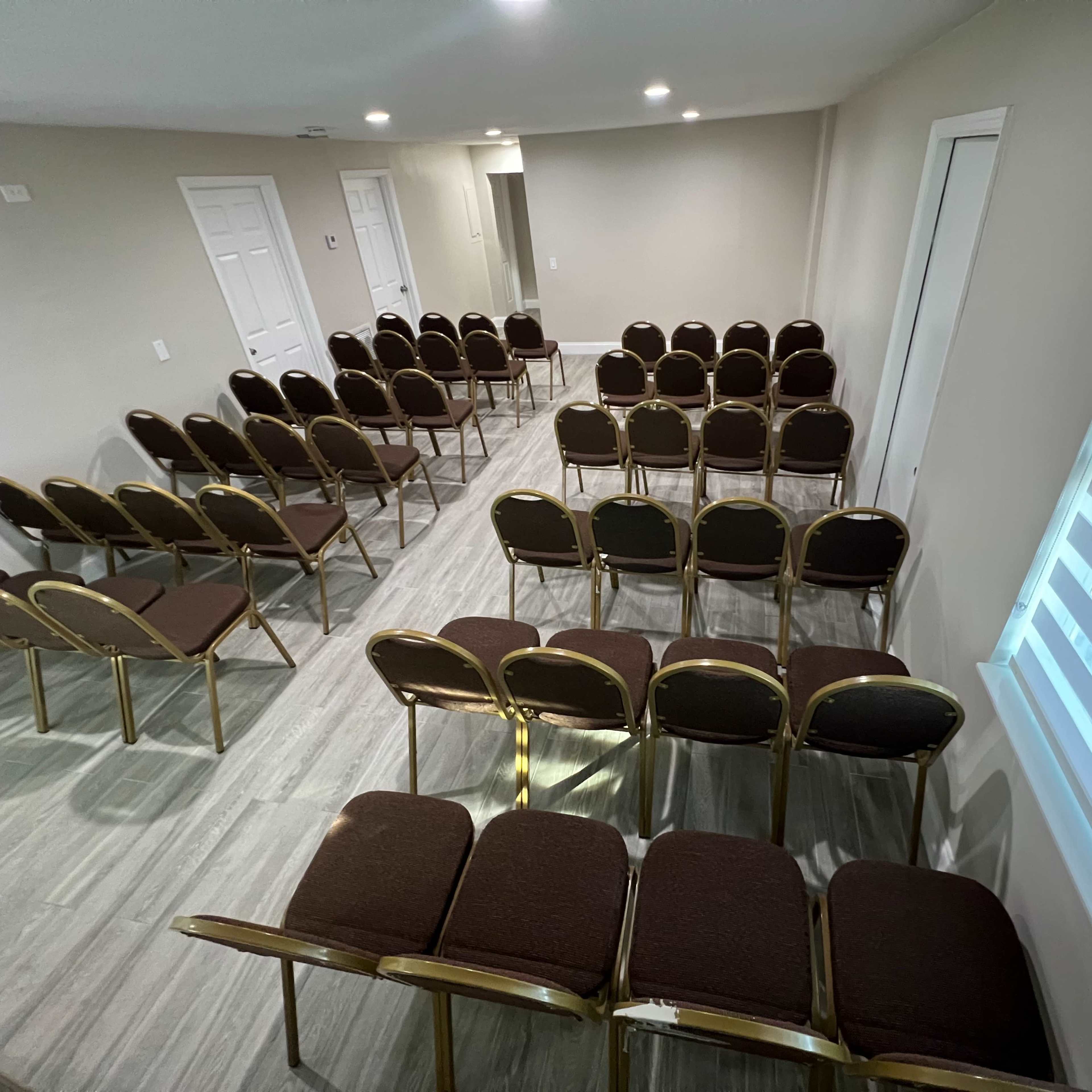 An empty room arranged with rows of brown chairs facing the front.