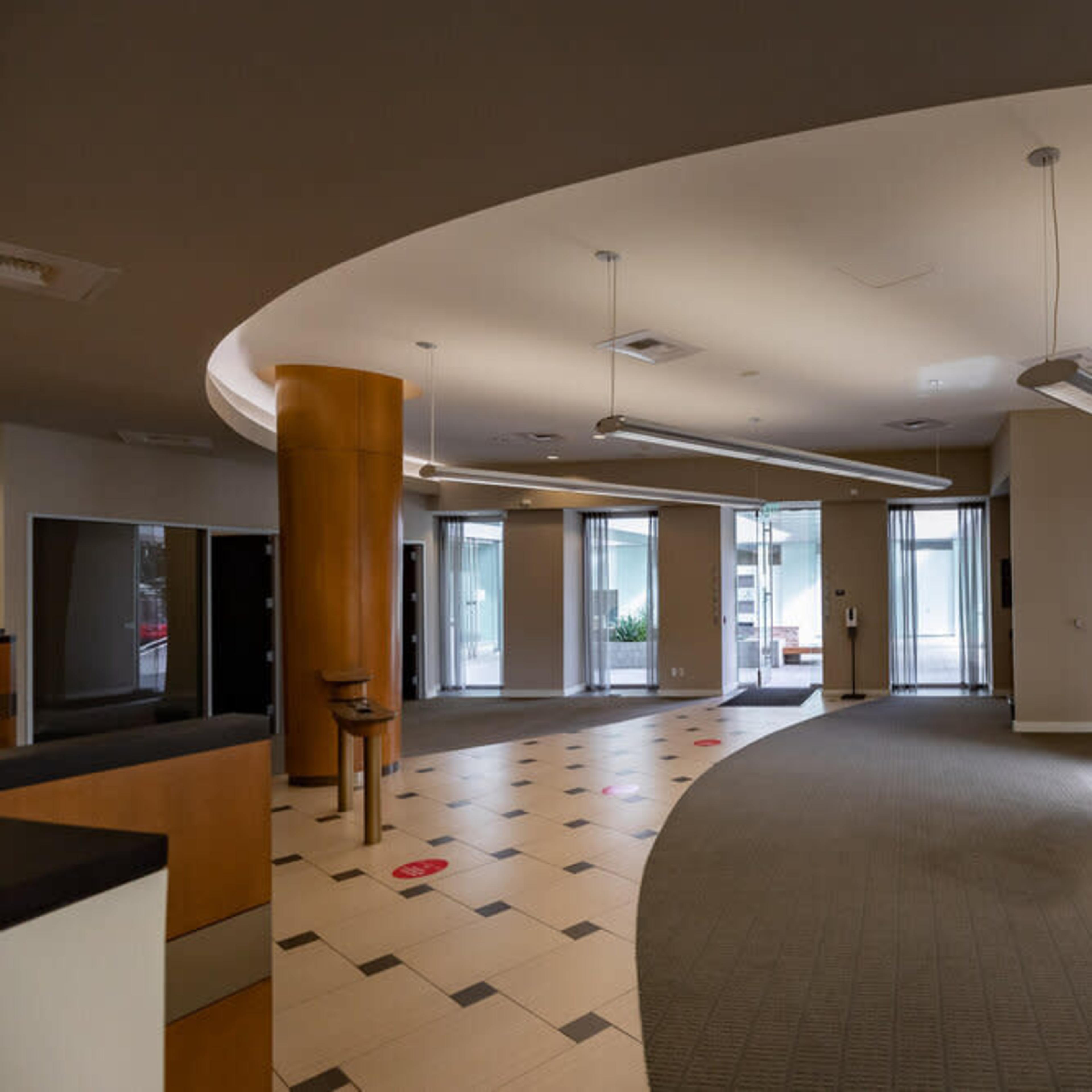 An empty office lobby featuring curved walls, recessed lighting, and a combination of carpet and tile flooring.