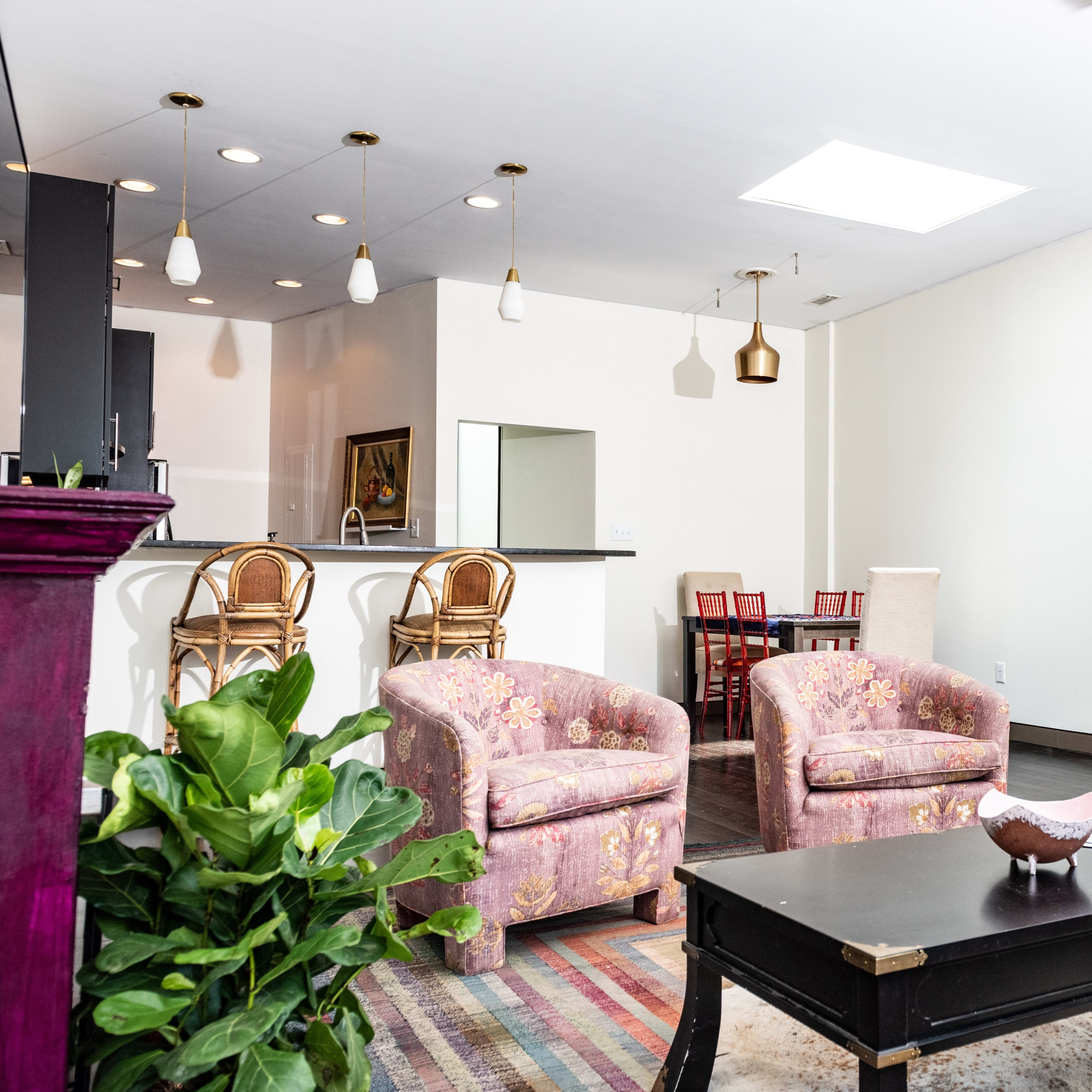 A modern living space with two floral-patterned armchairs, a coffee table, and a glimpse of a kitchen area in the background.
