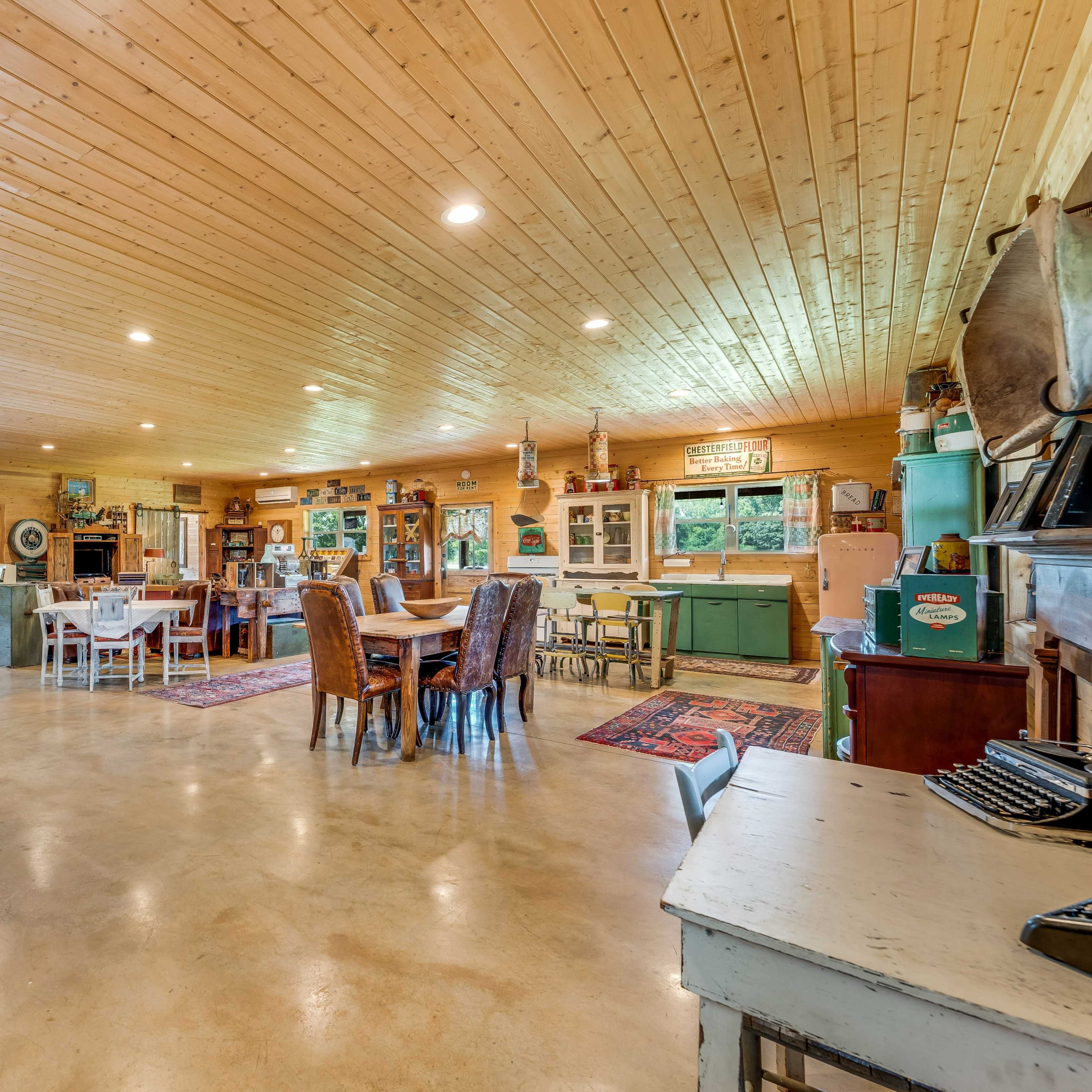 A spacious, warmly lit interior of a rustic room with wooden ceilings and a mix of dining and seating areas.