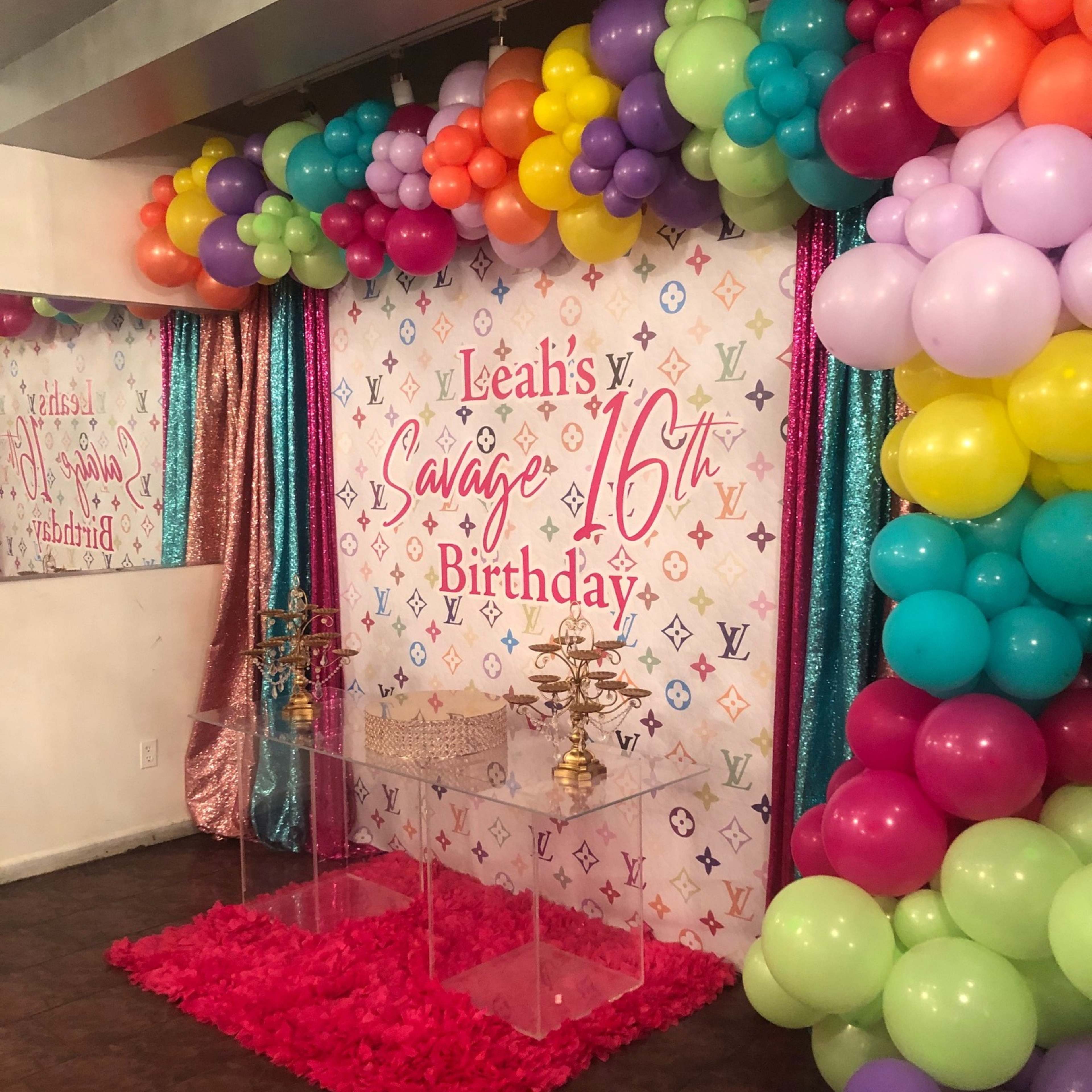 A colorful birthday backdrop with balloons and floral decor, celebrating "Leah's Savage 16th Birthday."