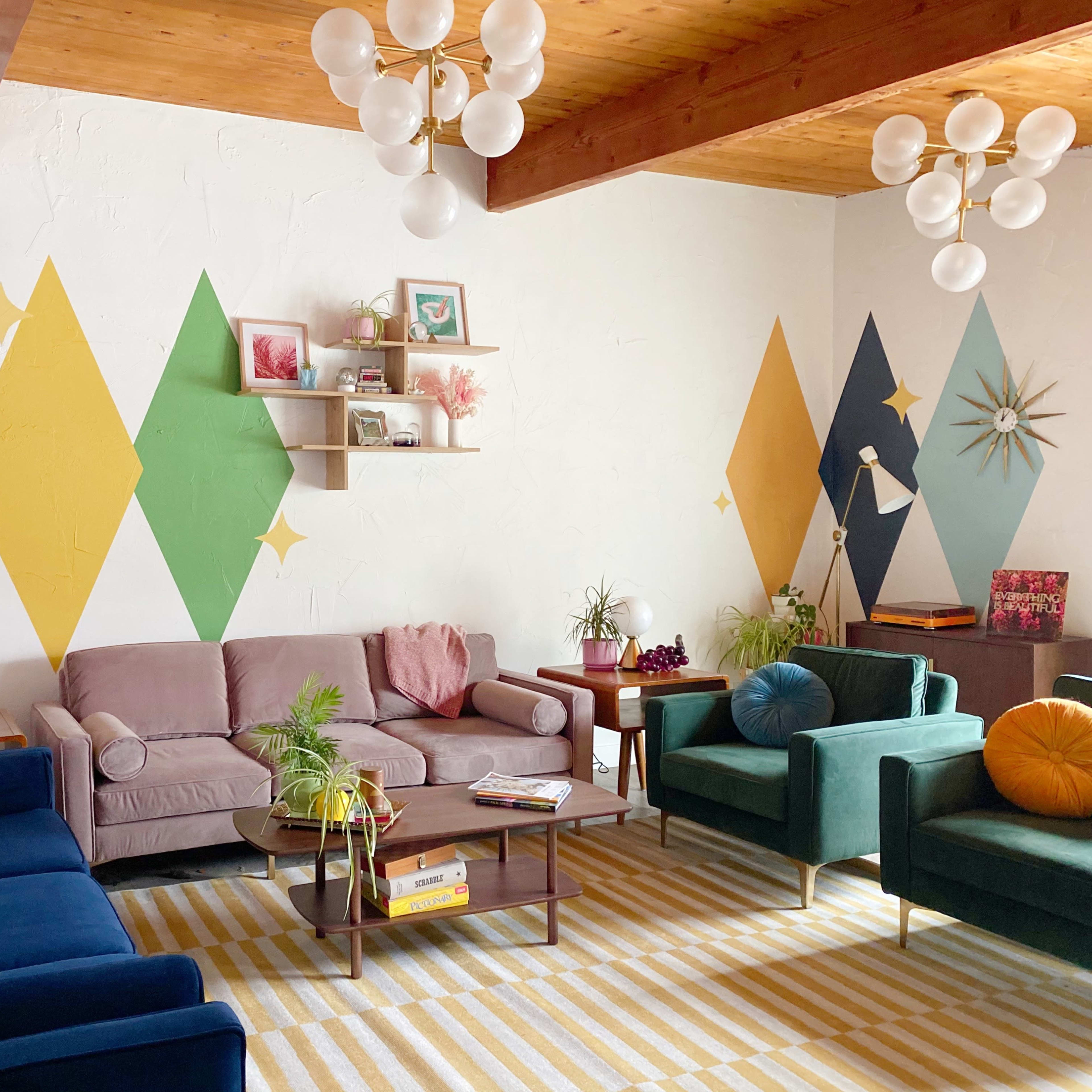 A brightly colored living room with a mix of sofas, plants, and geometric wall art.