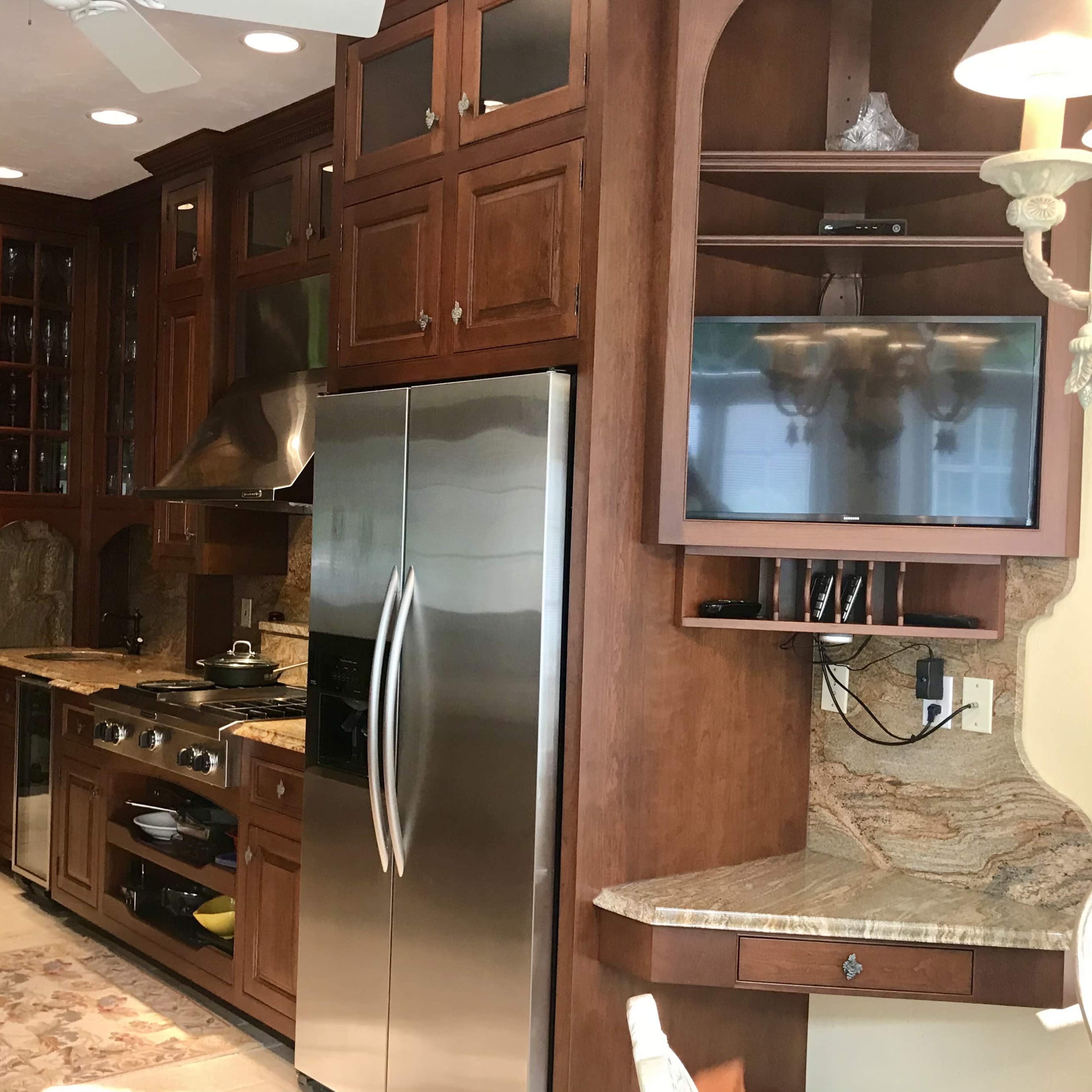 A modern kitchen featuring wooden cabinetry, stainless steel appliances, and a stone accent wall.