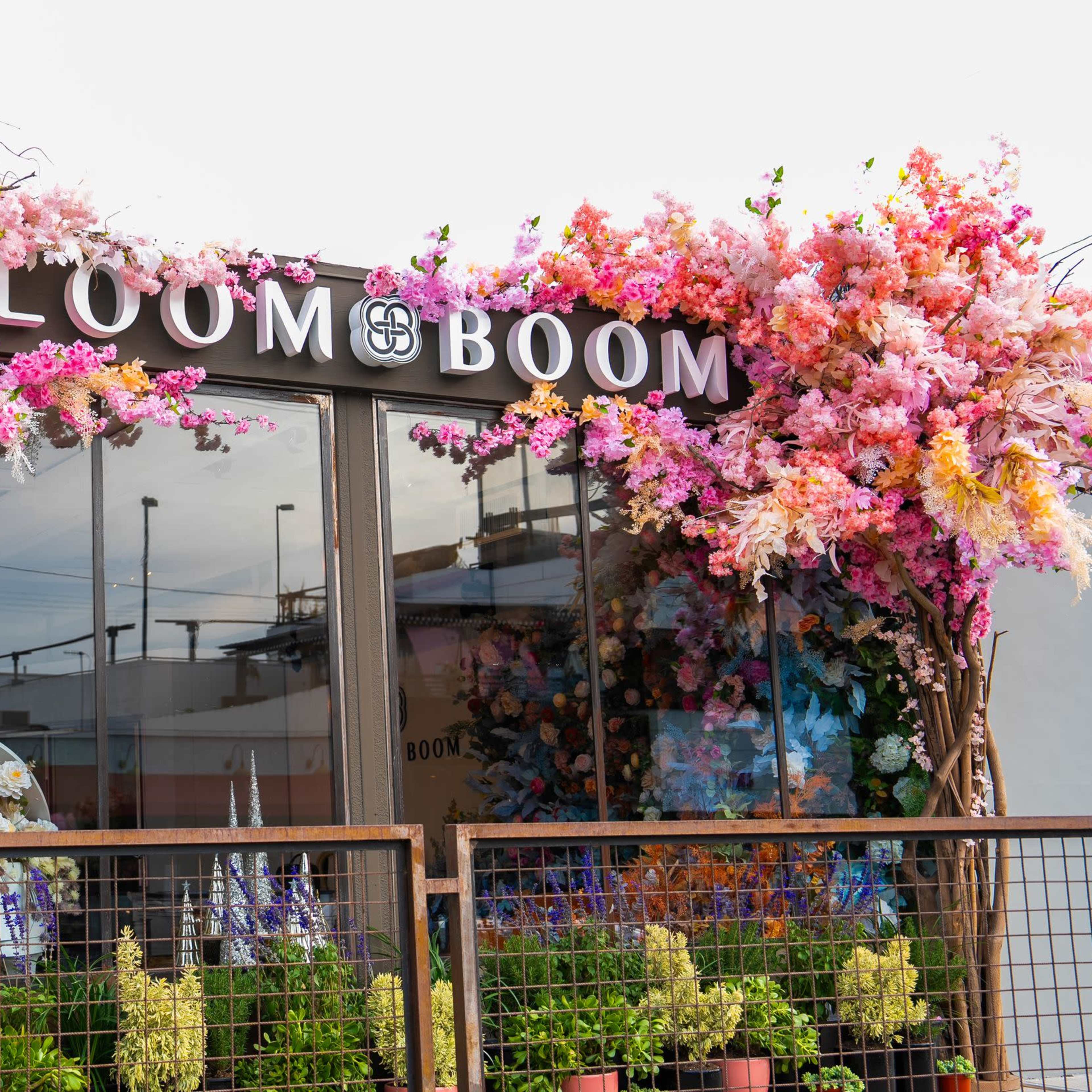 A storefront named "BLOOM BOOM" features vibrant floral decorations in pink and purple on its exterior.