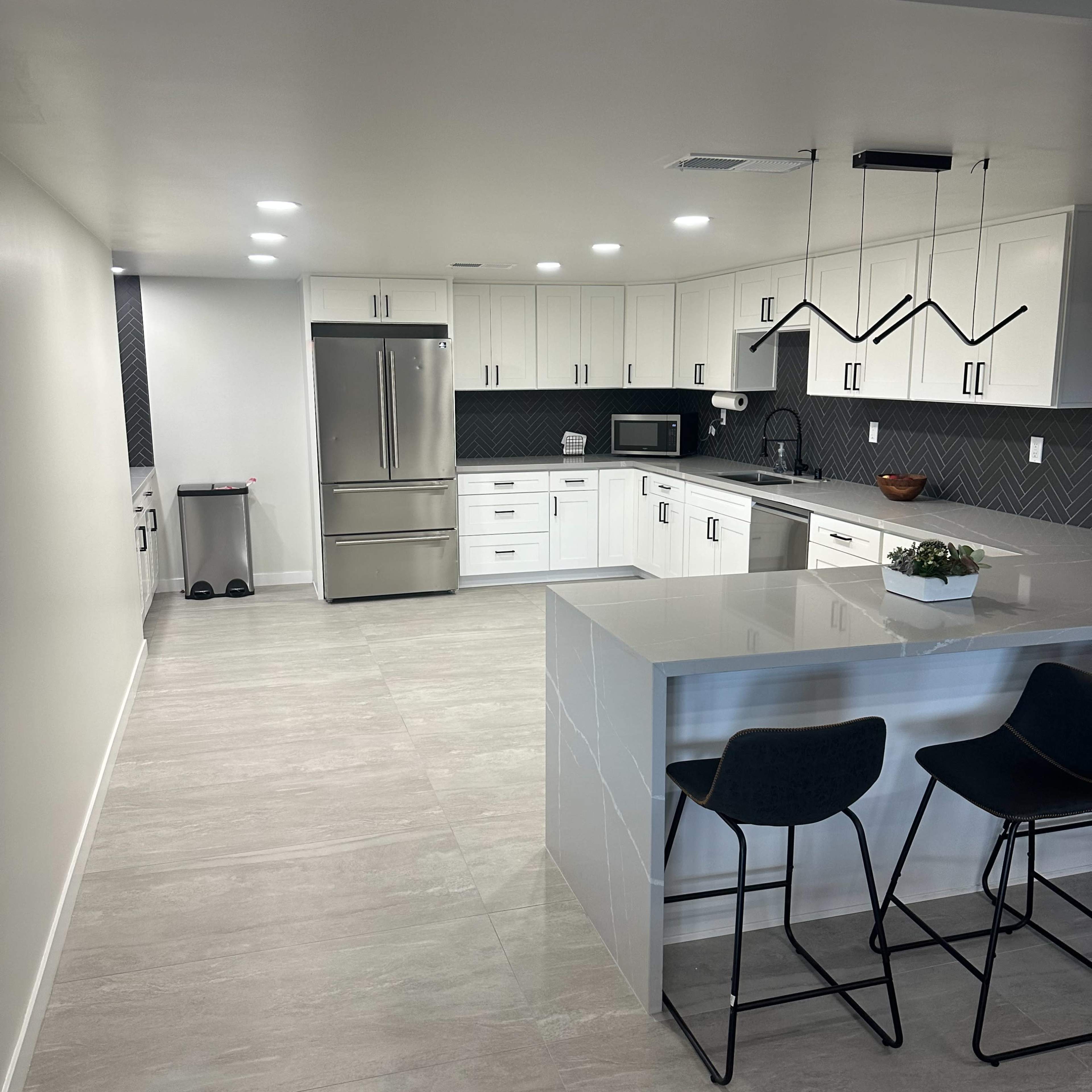 A modern kitchen with white cabinets, stainless steel appliances, and a large island with bar stools.