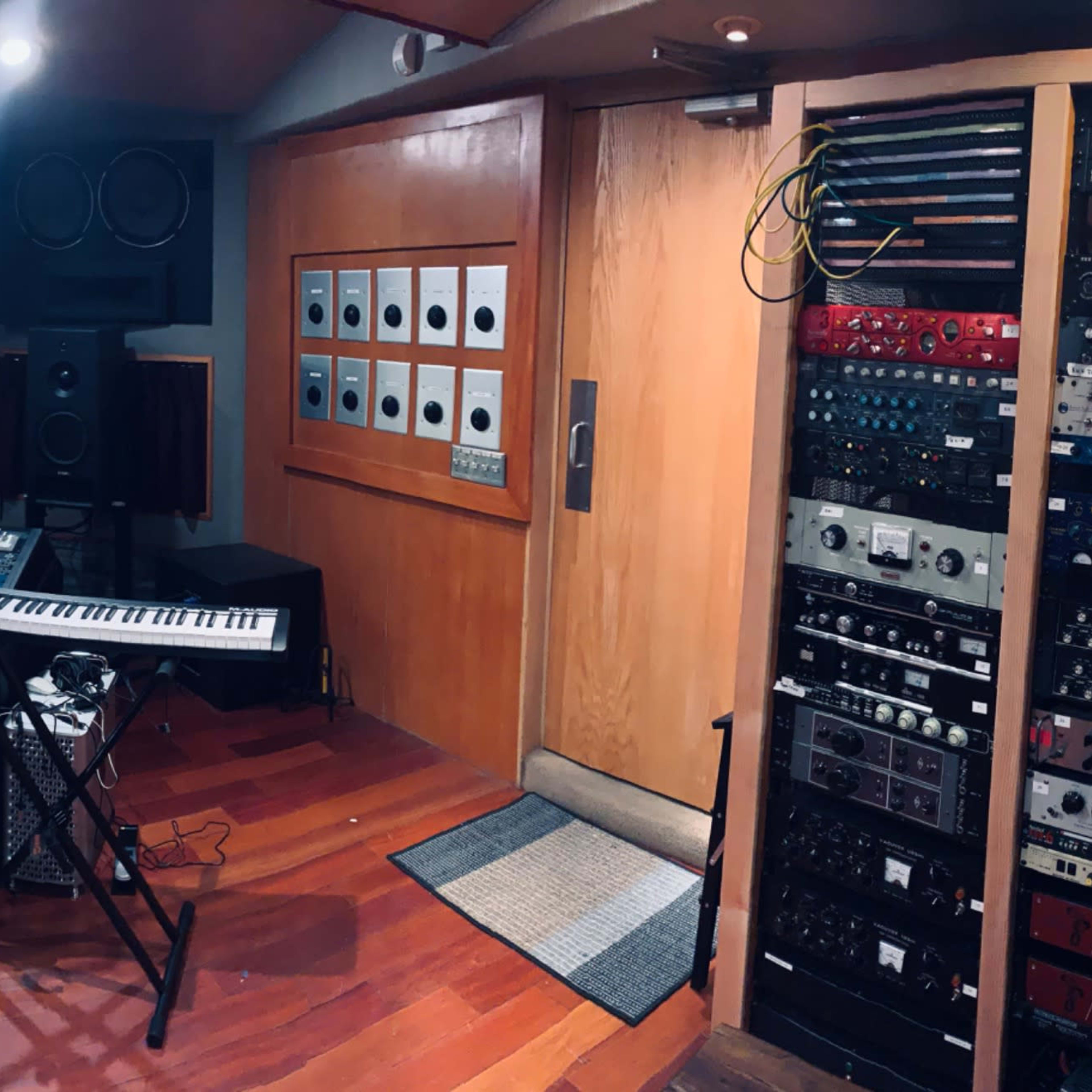 A well-equipped music studio featuring various audio equipment, a keyboard, and a computer setup in a wooden interior.