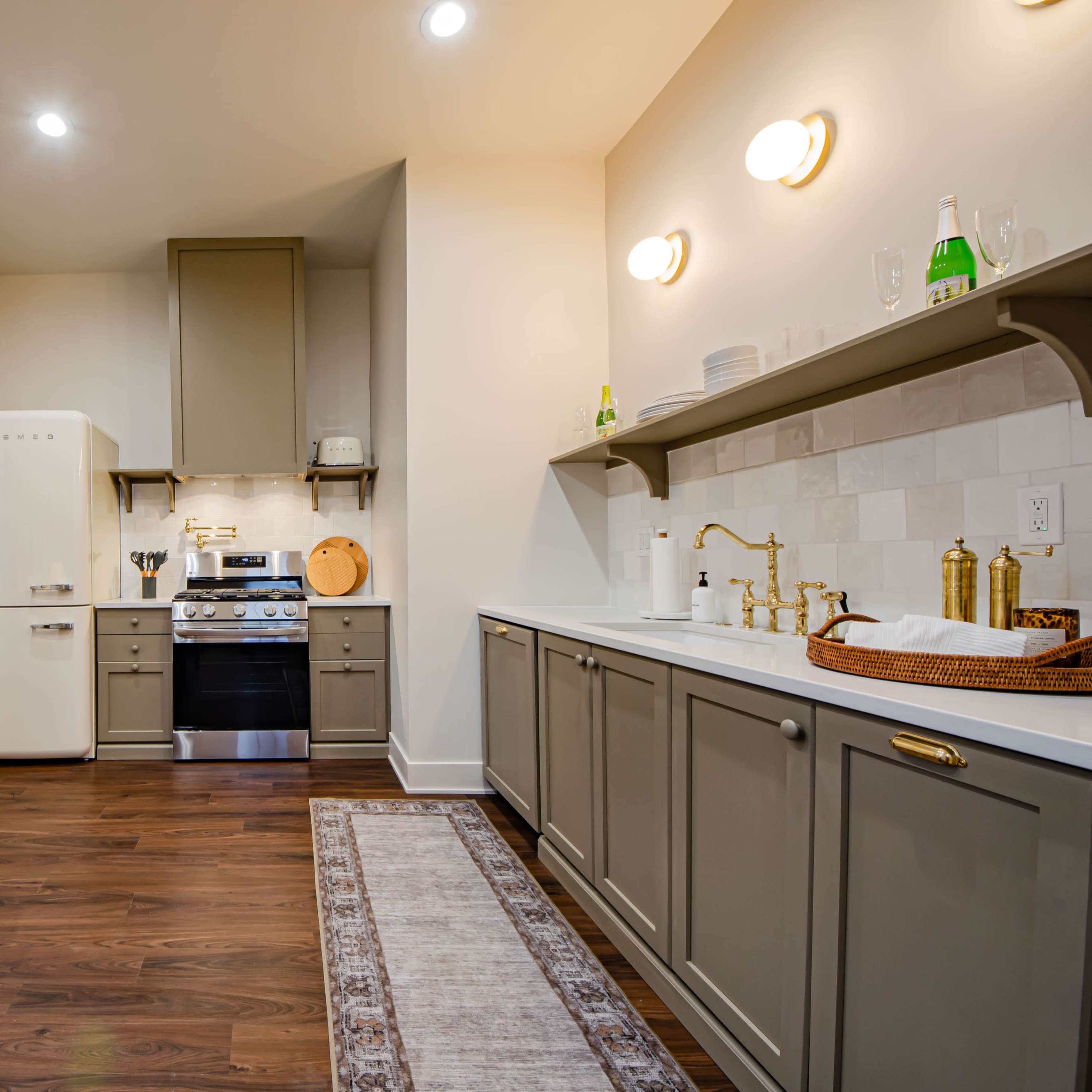 A modern kitchen features gray cabinetry, a vintage-style refrigerator, and a dining table in a well-lit space.