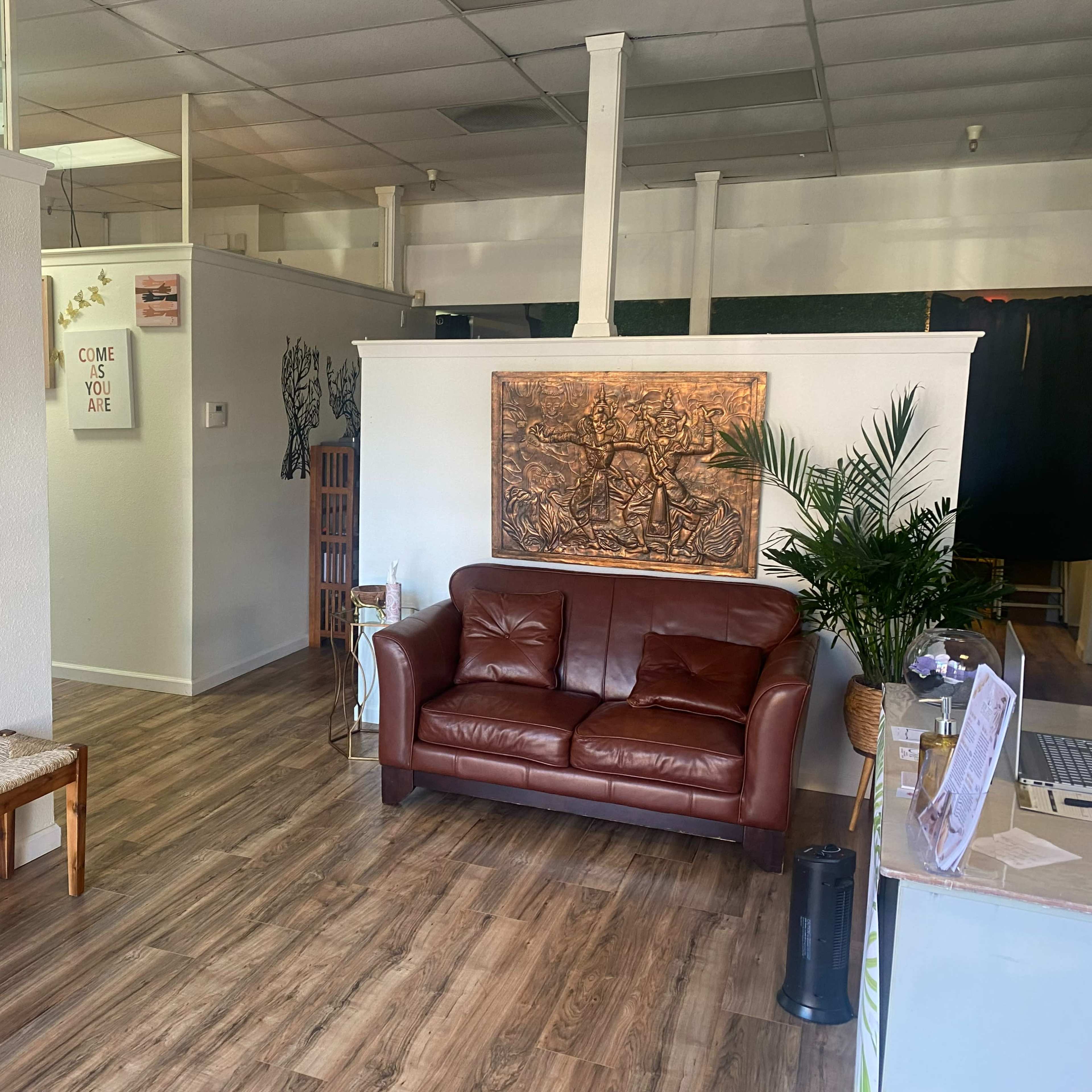 A spacious, well-lit interior with a leather couch, decorative wall art, and wooden flooring.