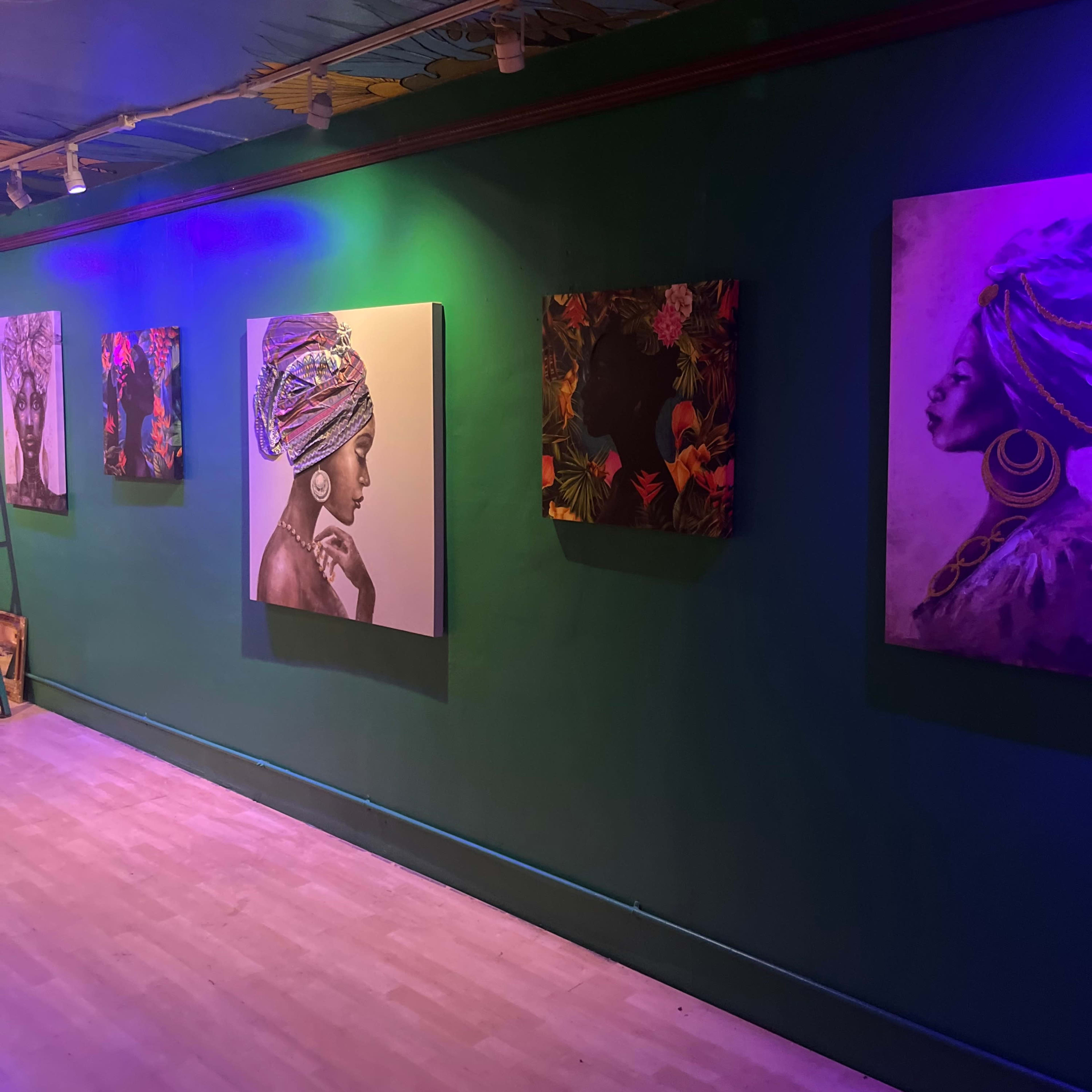 A gallery wall featuring several portraits of women, each depicted in different artistic styles, set against a green wall illuminated with purple lighting.