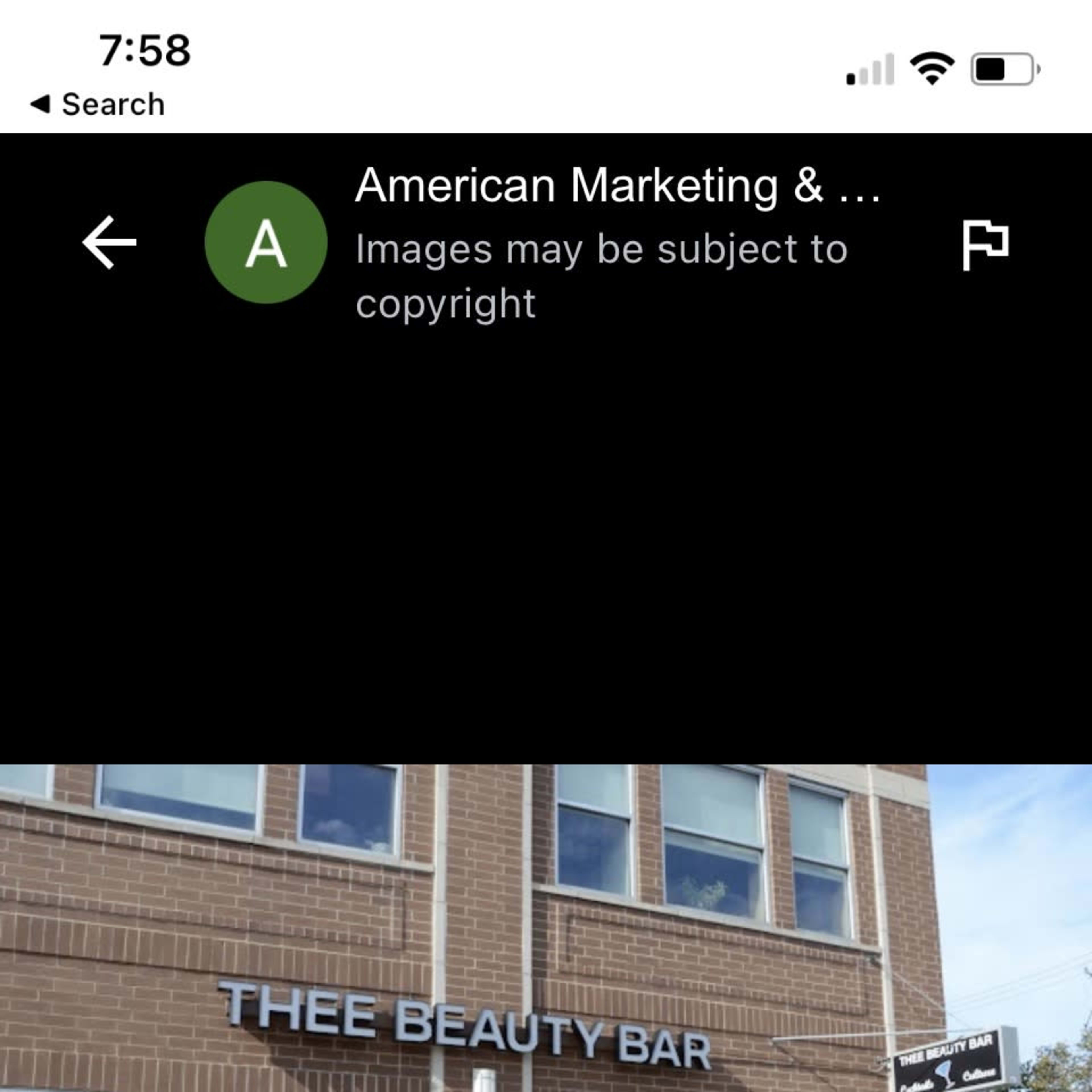 A brick building with large windows, featuring a sign that reads "THEE BEAUTY BAR."