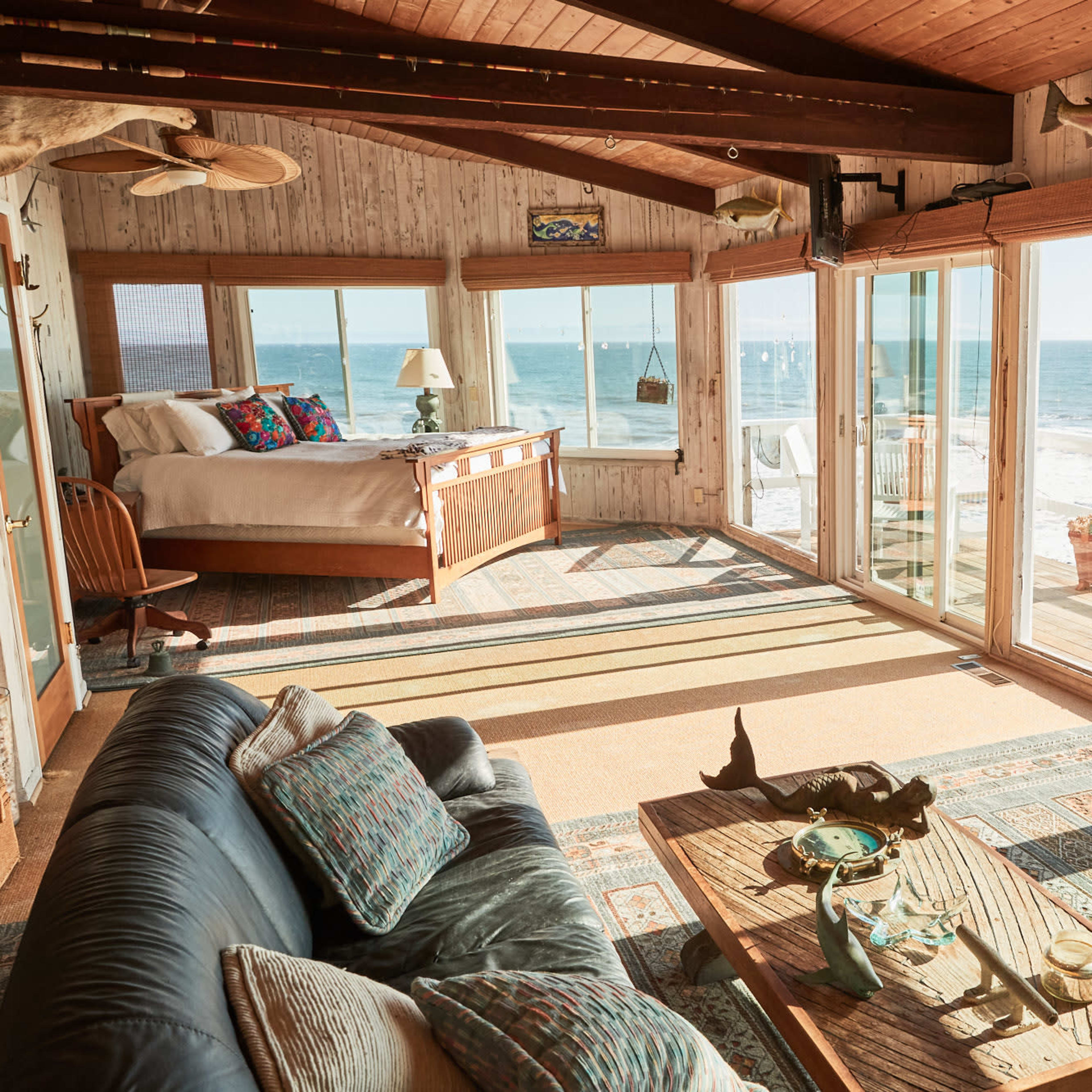 A cozy beachfront room with large glass doors overlooking the ocean, featuring a bed, sofa, and a coffee table.