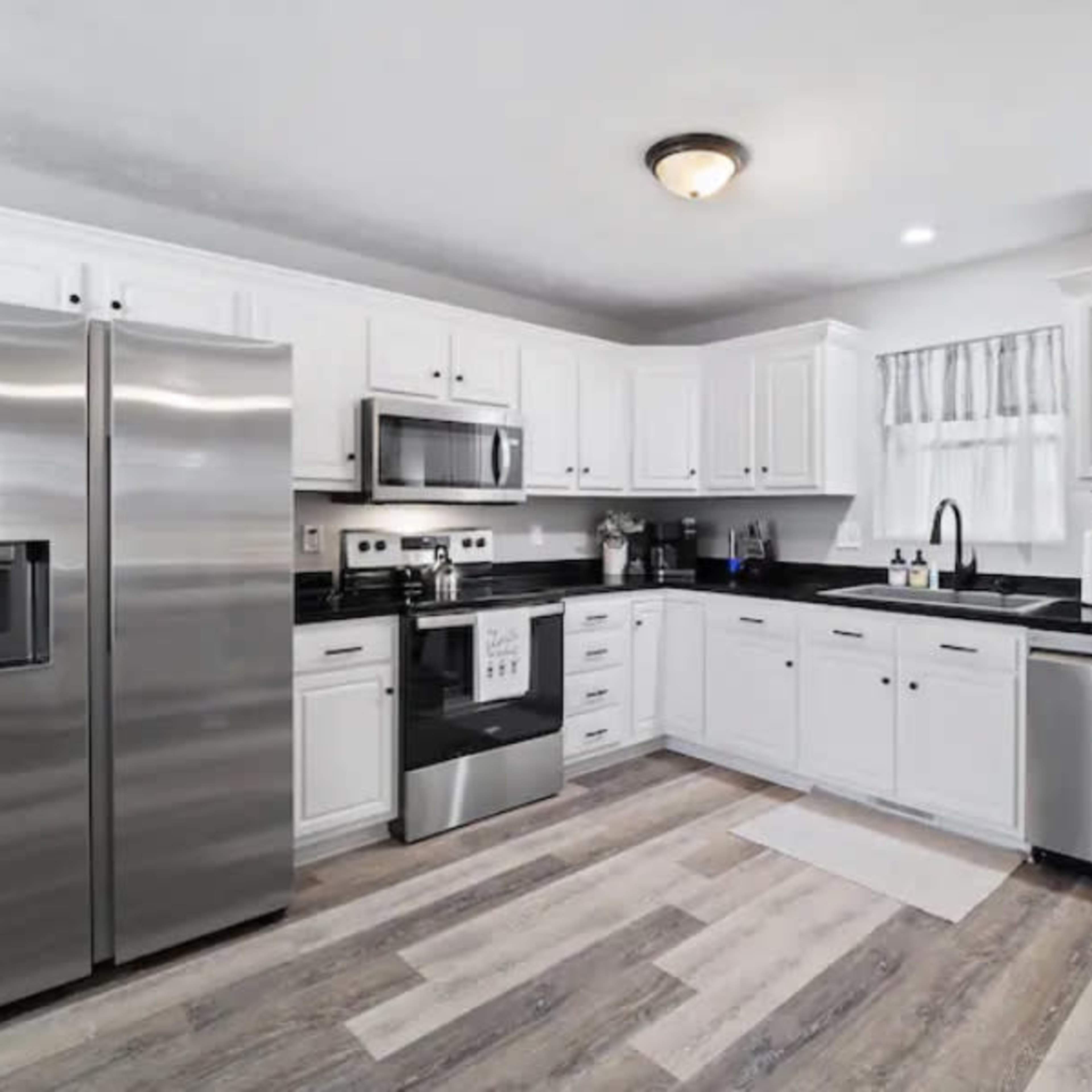 A modern kitchen with white cabinets, stainless steel appliances, and a dark countertop.