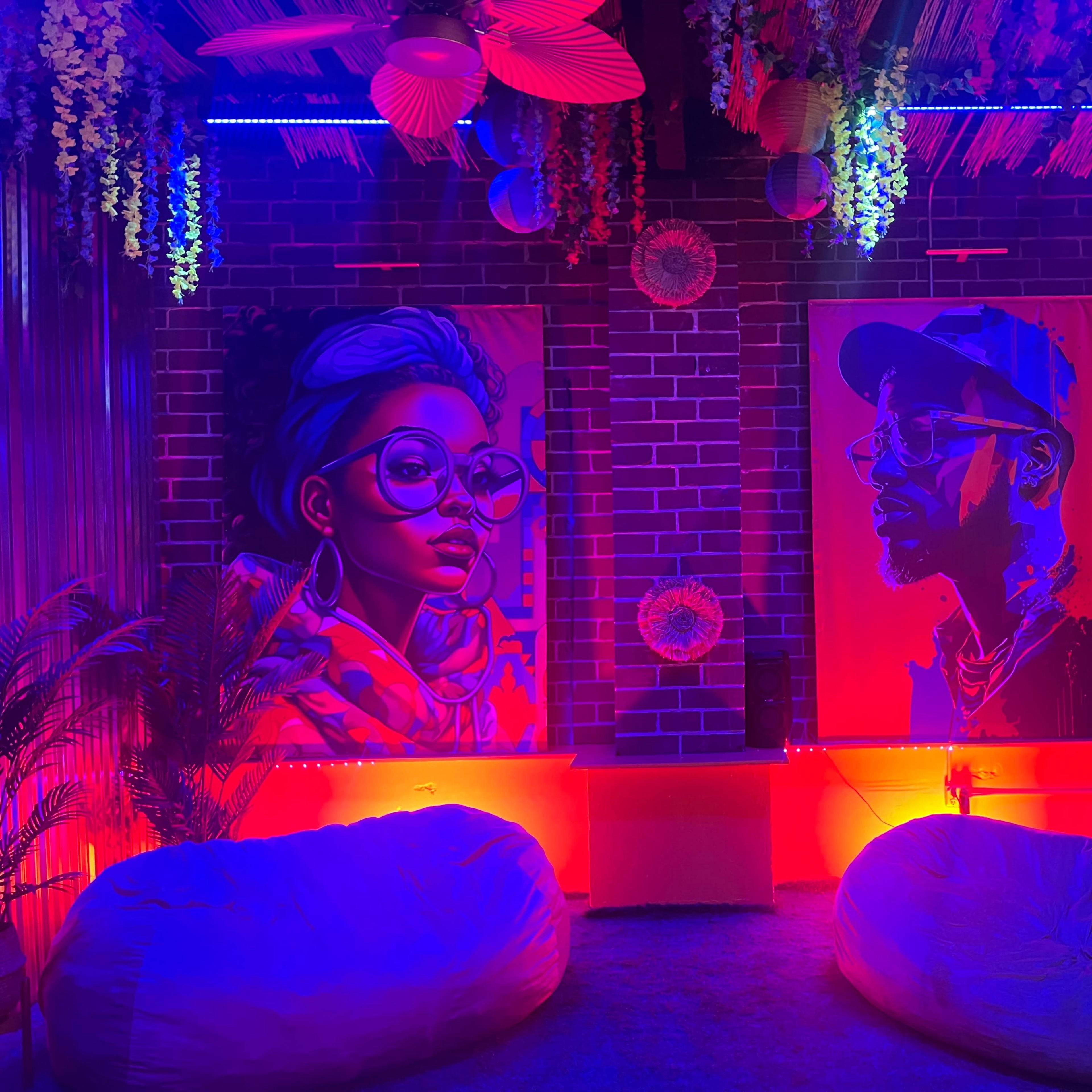 A vibrant indoor lounge area decorated with green foliage, colorful accents, and seating arrangements on a grassy floor.