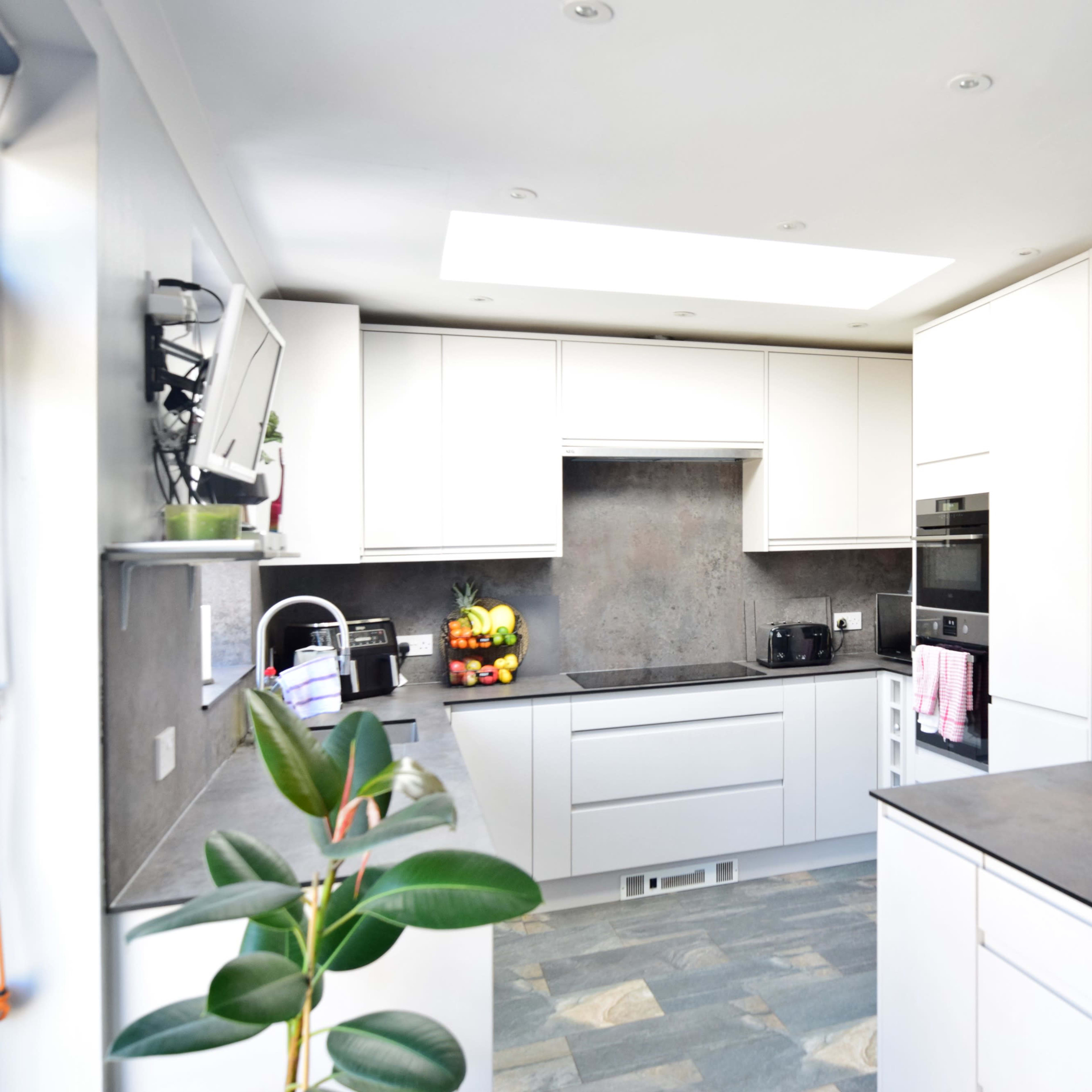 A modern kitchen features white cabinetry, a dark countertop, and pendant lighting above an island.