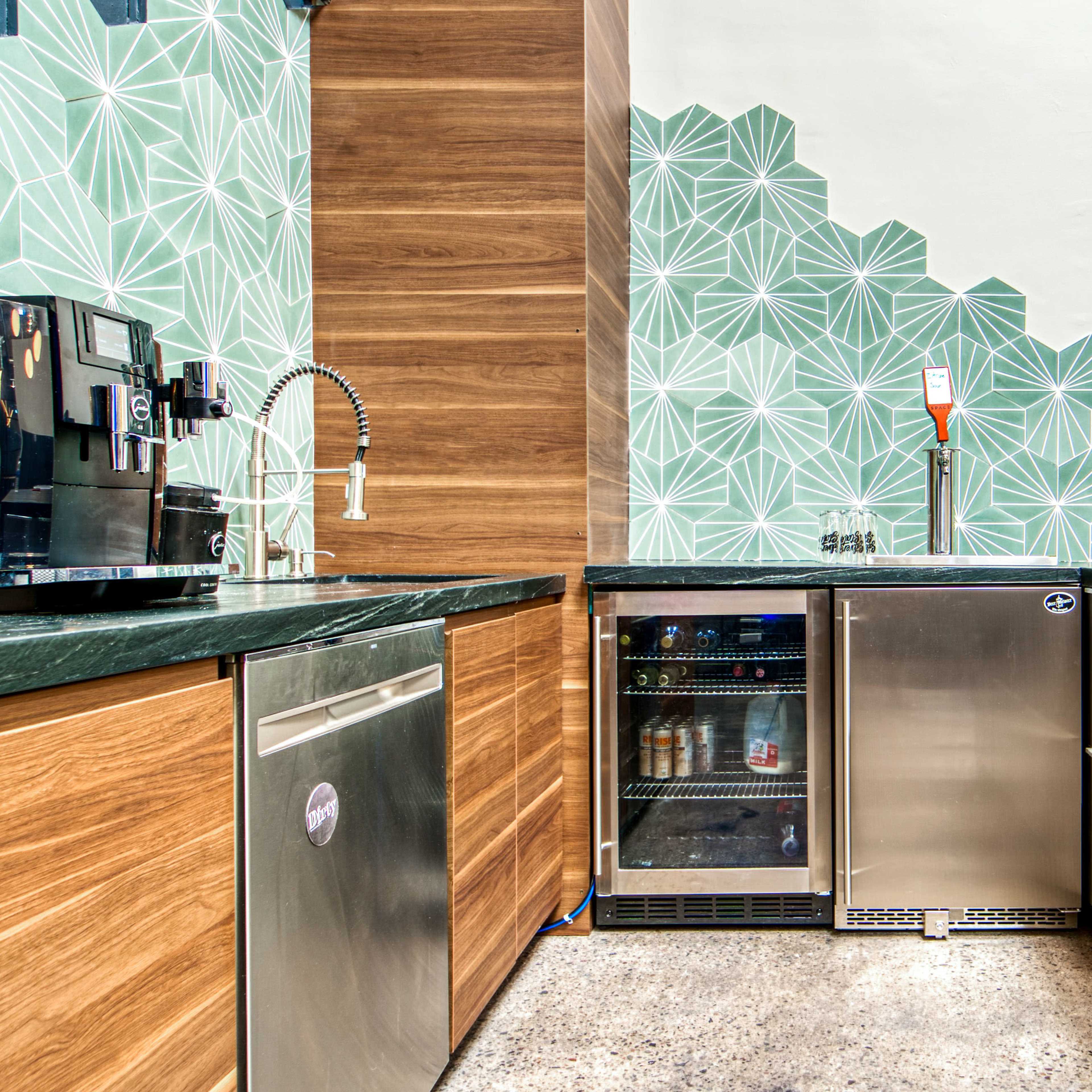 A modern kitchen with wooden cabinets, stainless steel appliances, and a geometric patterned wall.