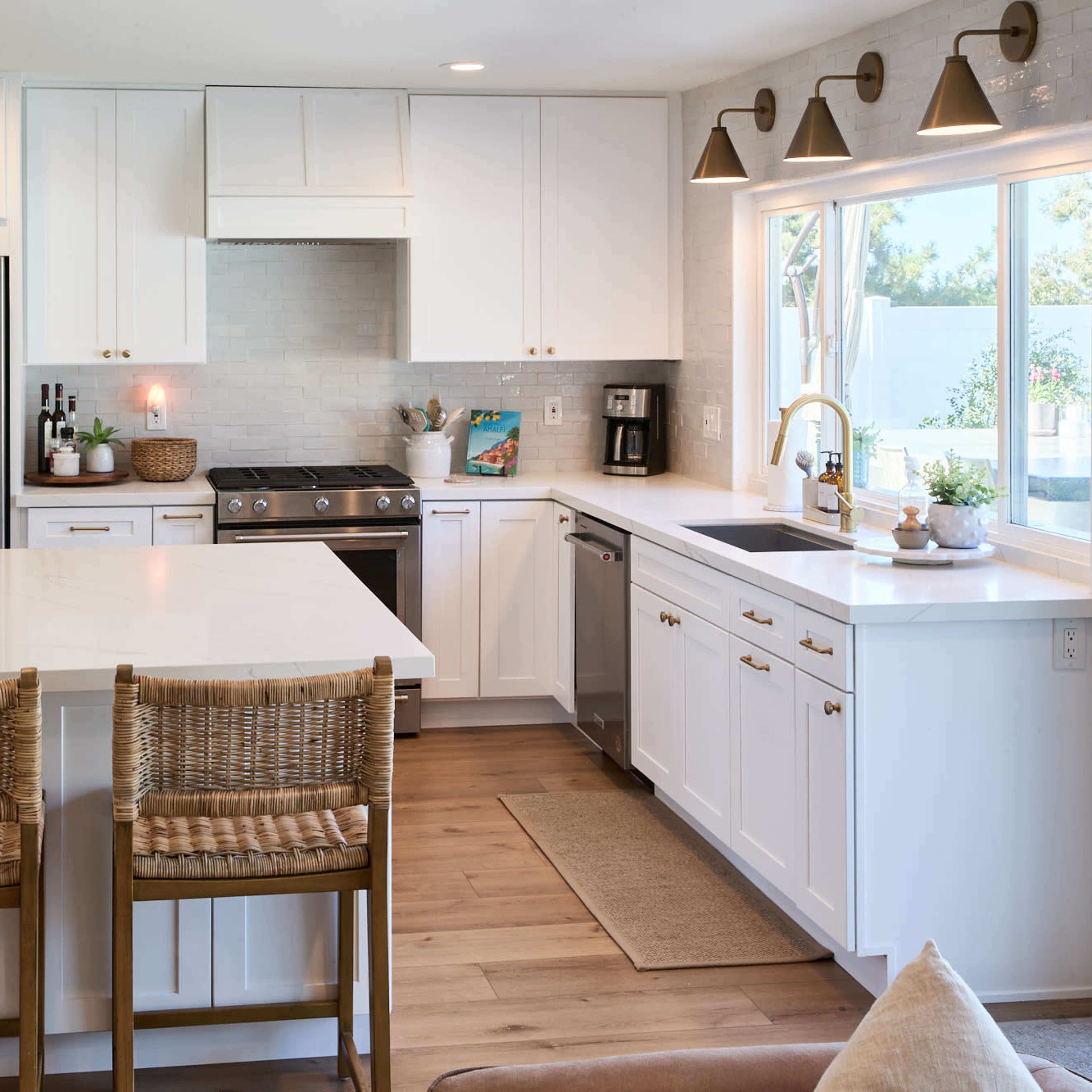 A modern kitchen with white cabinetry, stainless steel appliances, and a large island with bar stools.