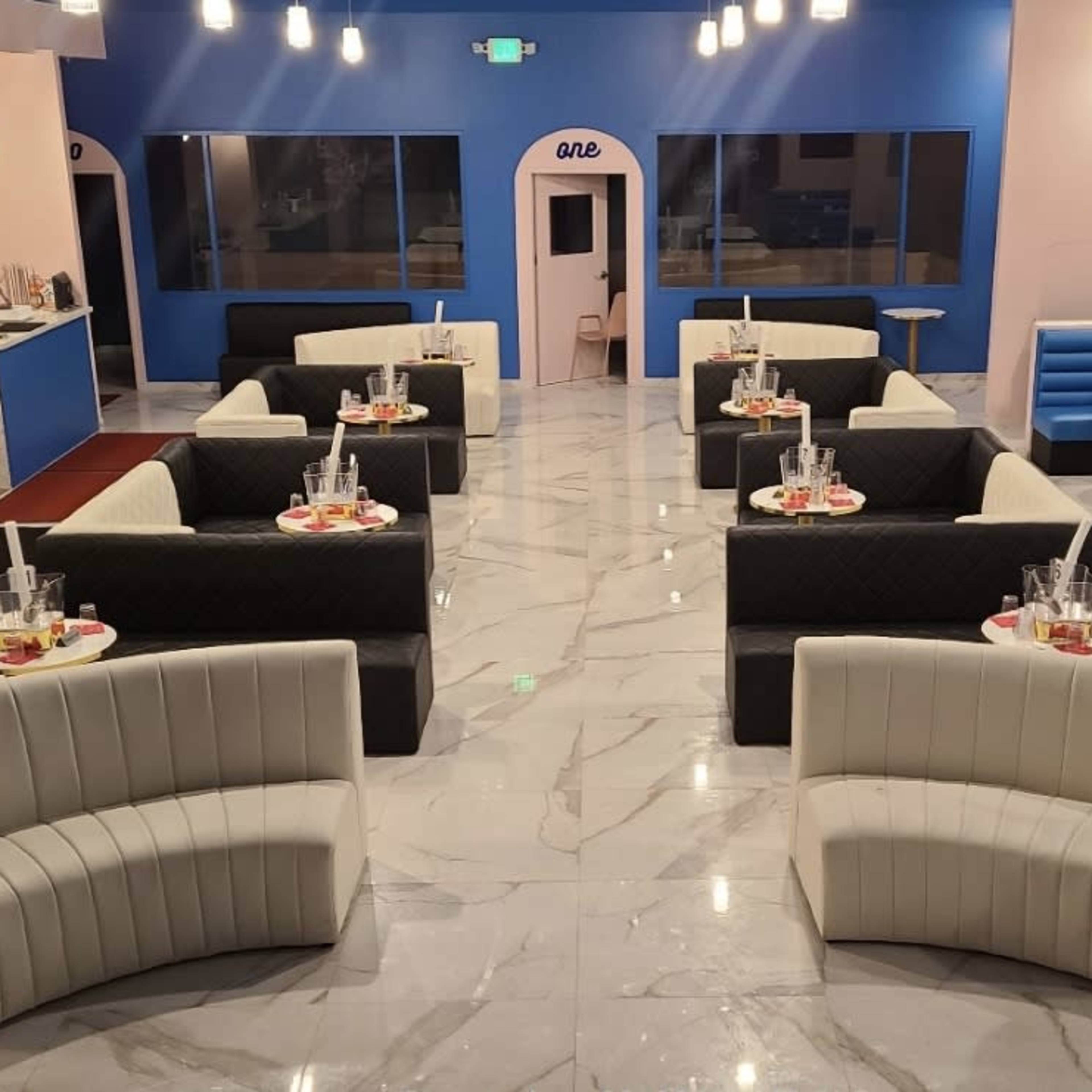 A modern lounge area with curved seating arrangements, marble flooring, and a bright color scheme featuring blue and pink walls.