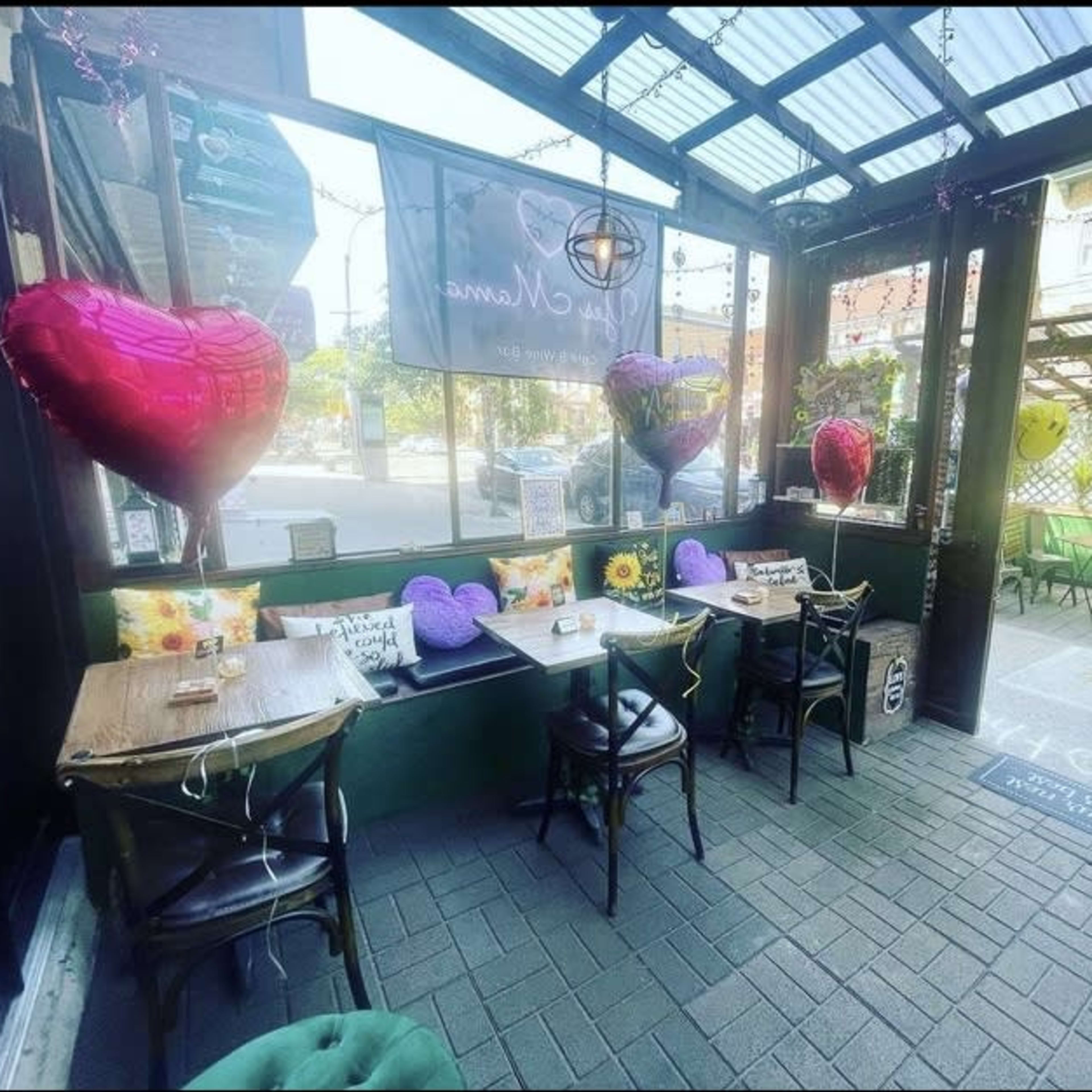 A cozy cafe patio adorned with heart-shaped balloons and tables set for guests.