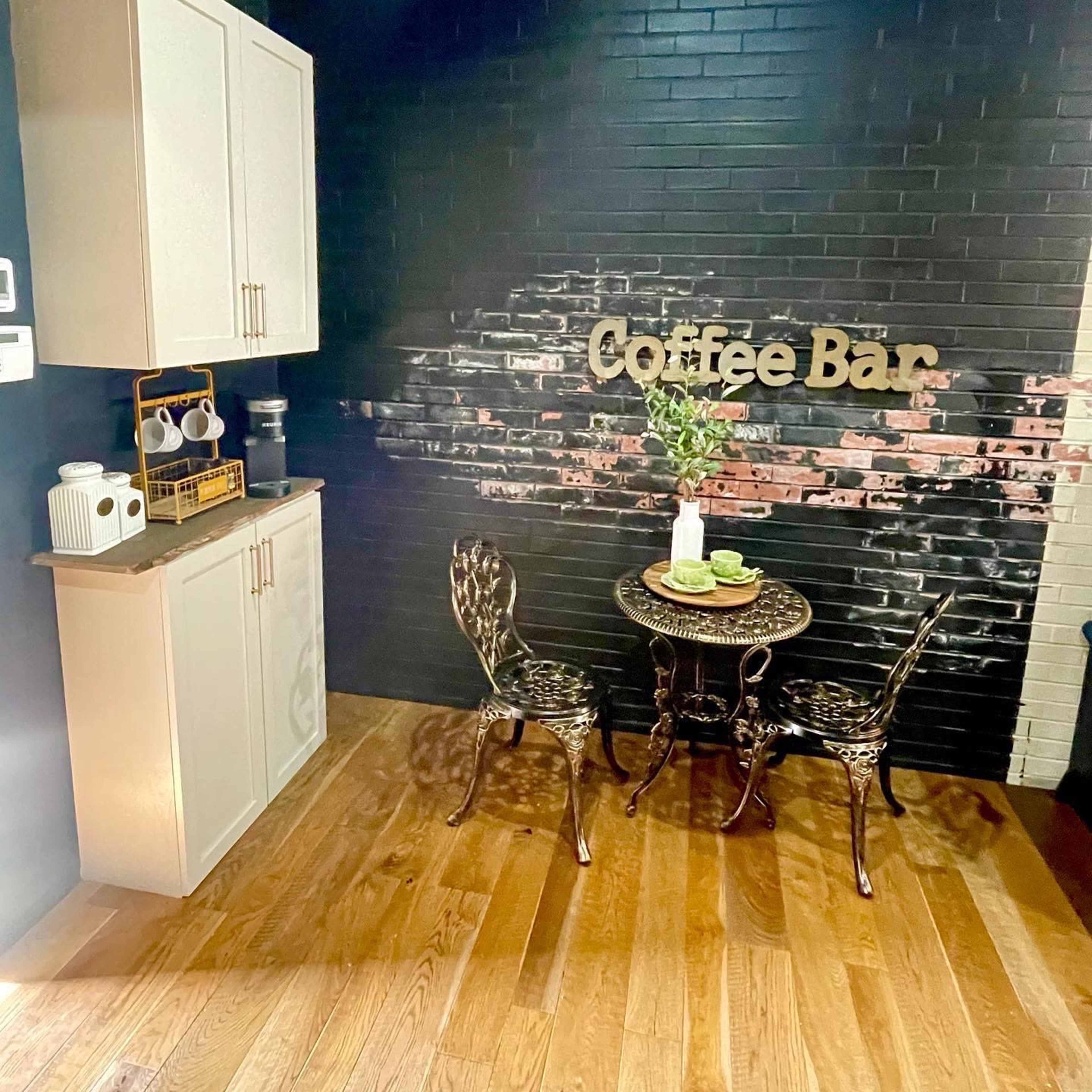 The scene features a small coffee bar setup with a table and two chairs against a black-brick wall, decorated with the words "Coffee Bar."