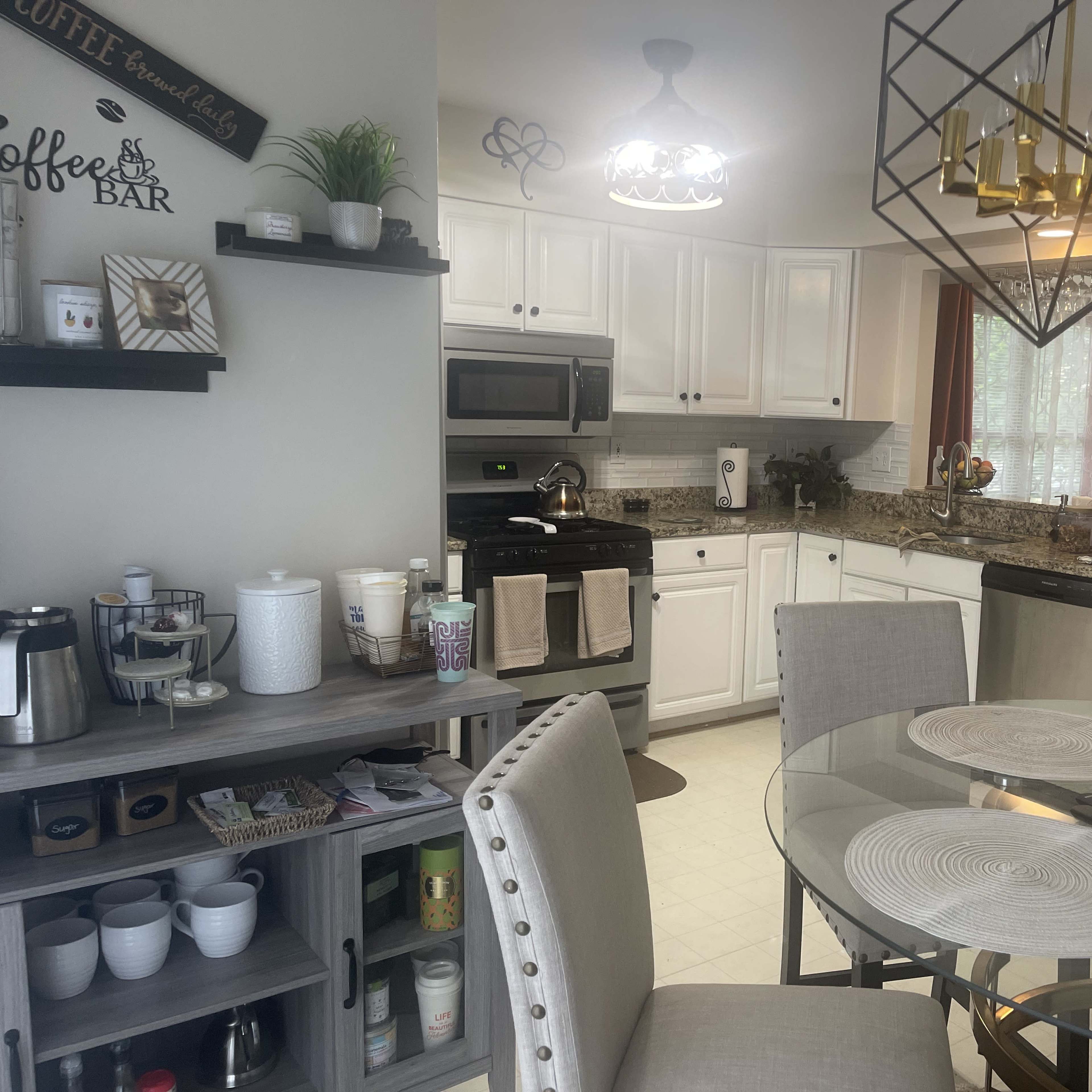 A modern kitchen with white cabinetry, granite countertops, and a dining table set for four.