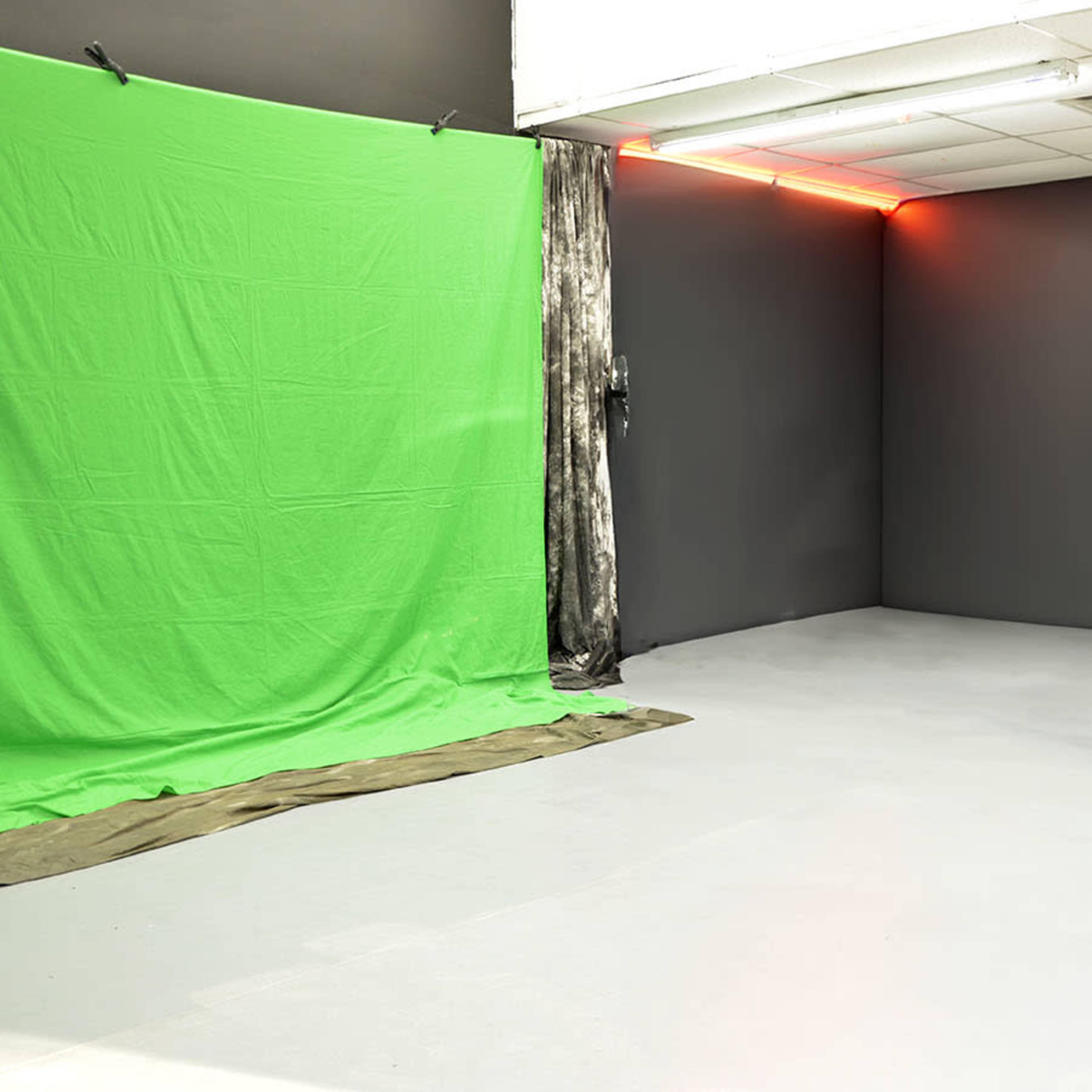 A studio setup featuring a green screen on the left, a white backdrop on the right, and a fog machine producing mist near the center.