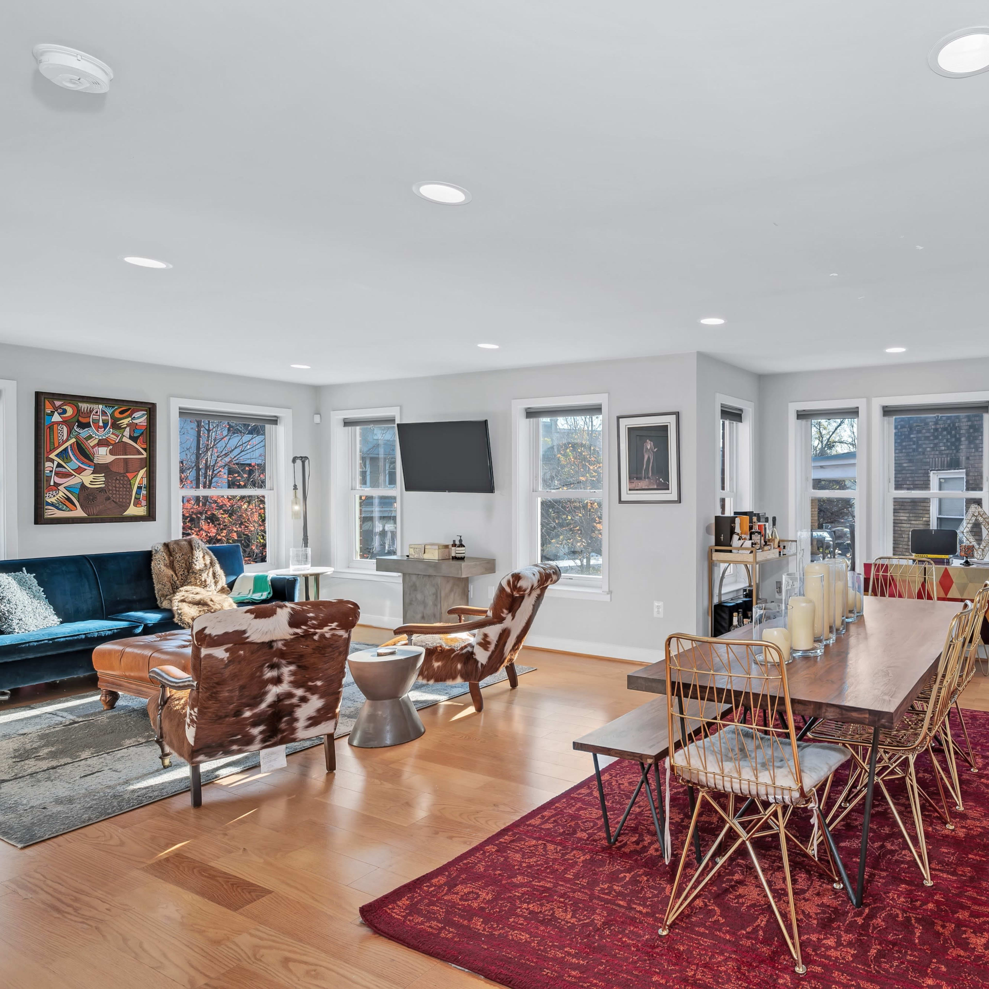A bright, open living and dining area with a large table, chairs, and a mix of modern and eclectic décor.