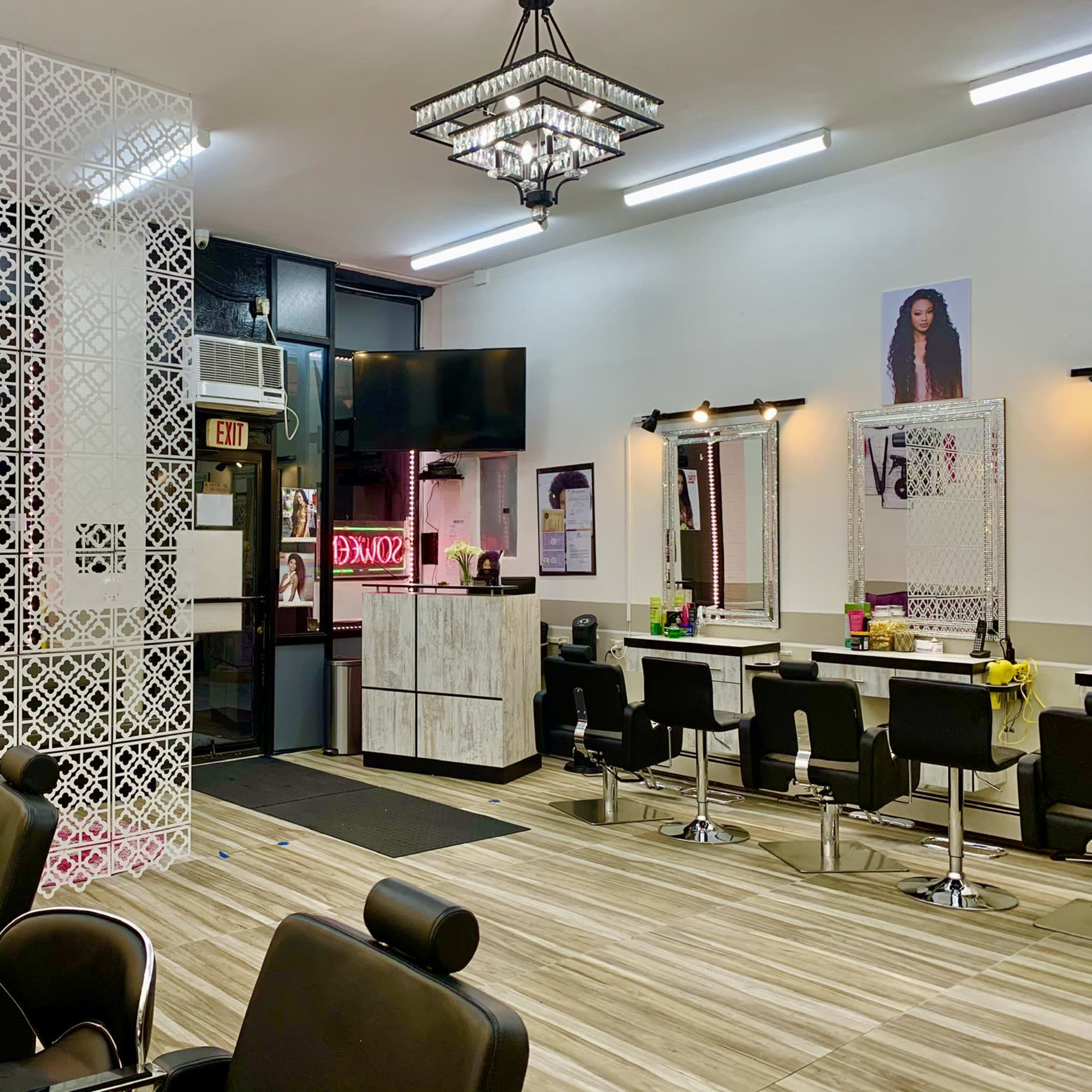 A modern hair salon with black styling chairs, mirrored stations, and decorative partition screens.