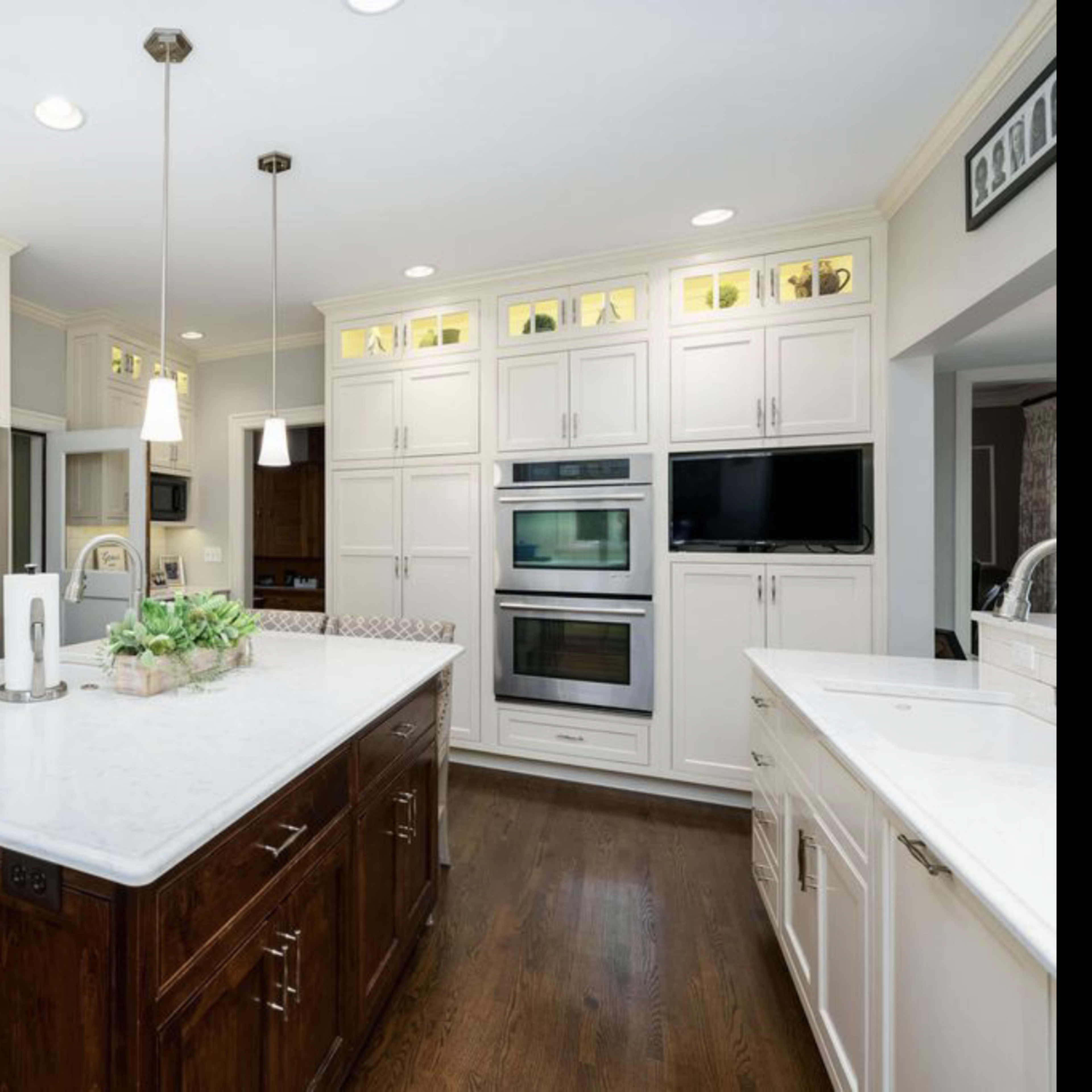 A modern kitchen with white cabinetry, a large marble island, and stainless steel appliances.