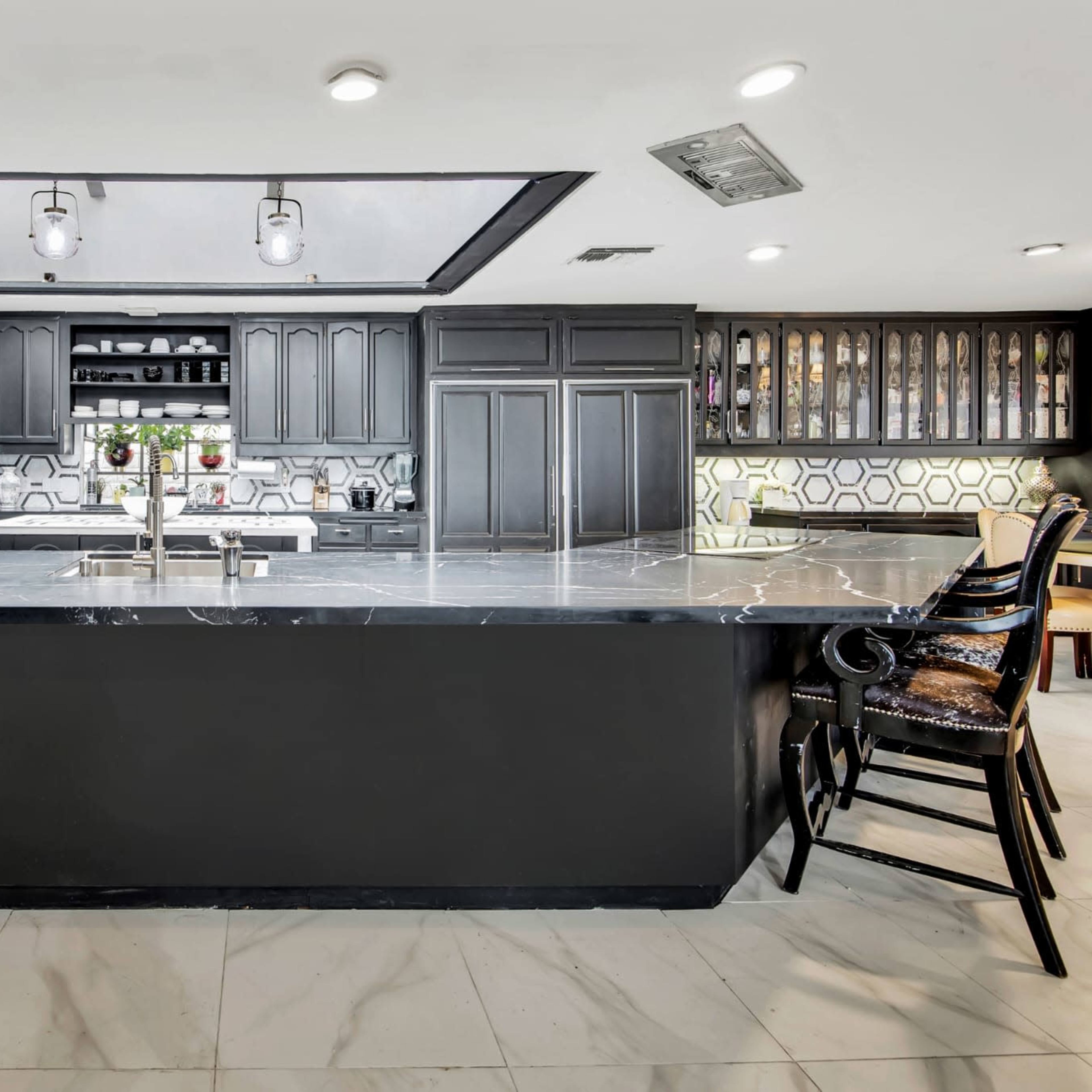 The kitchen features a large black island with a marble countertop, black cabinetry, and modern appliances.
