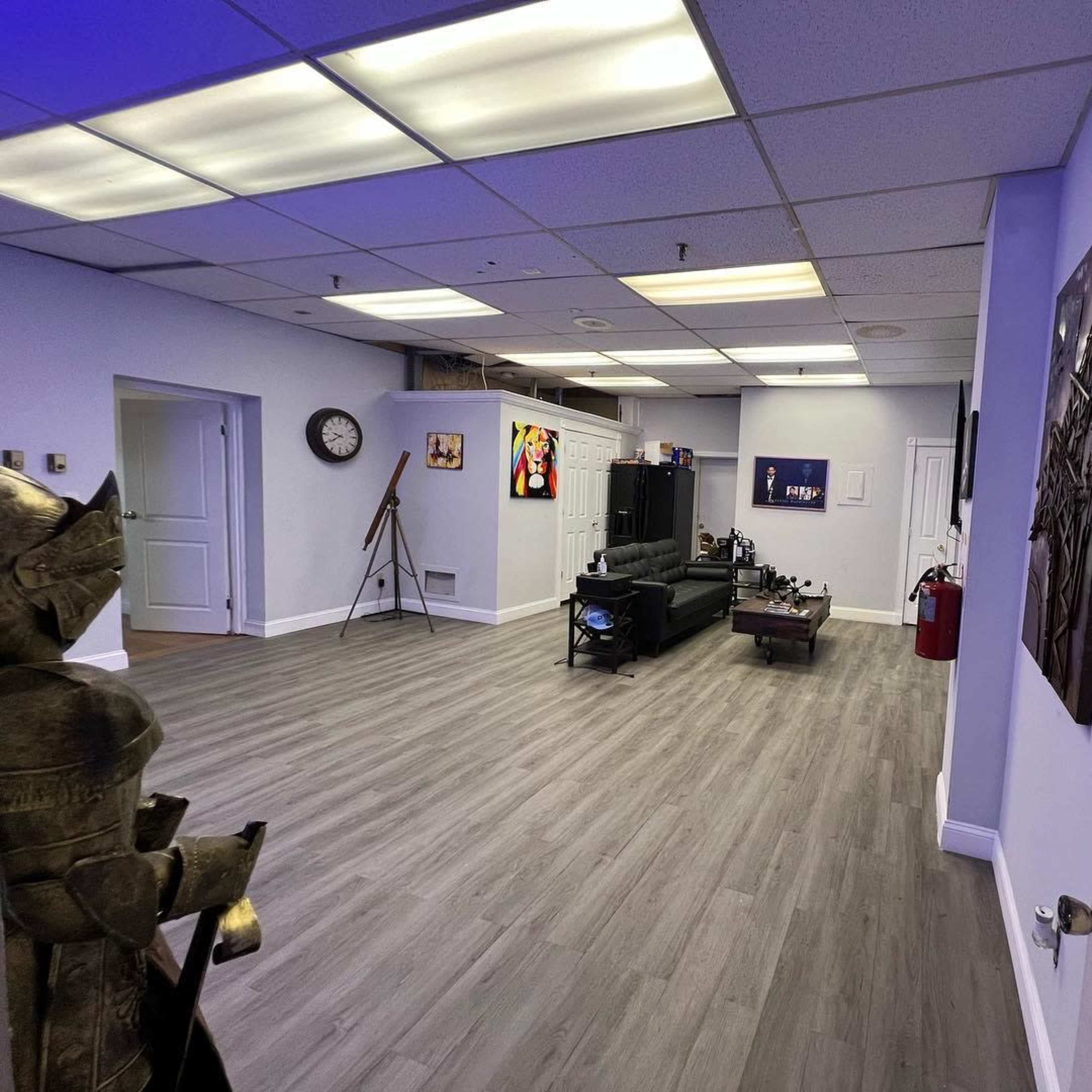 A spacious room with gray flooring, featuring a seating area, wall art, and a decorative figure on the left.