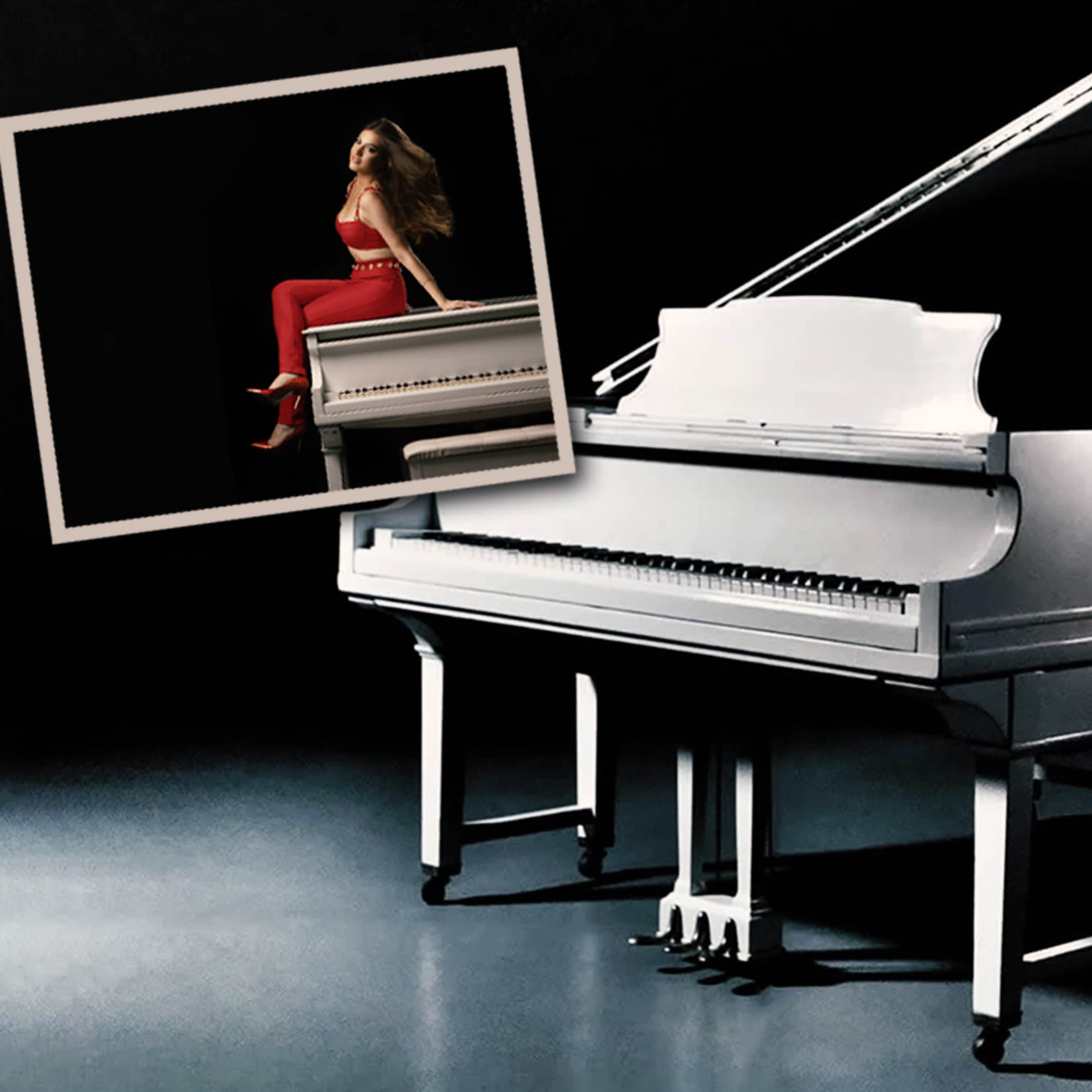 A grand white piano is positioned on a dark stage, with a framed image of a woman in a red outfit sitting on top of the piano.