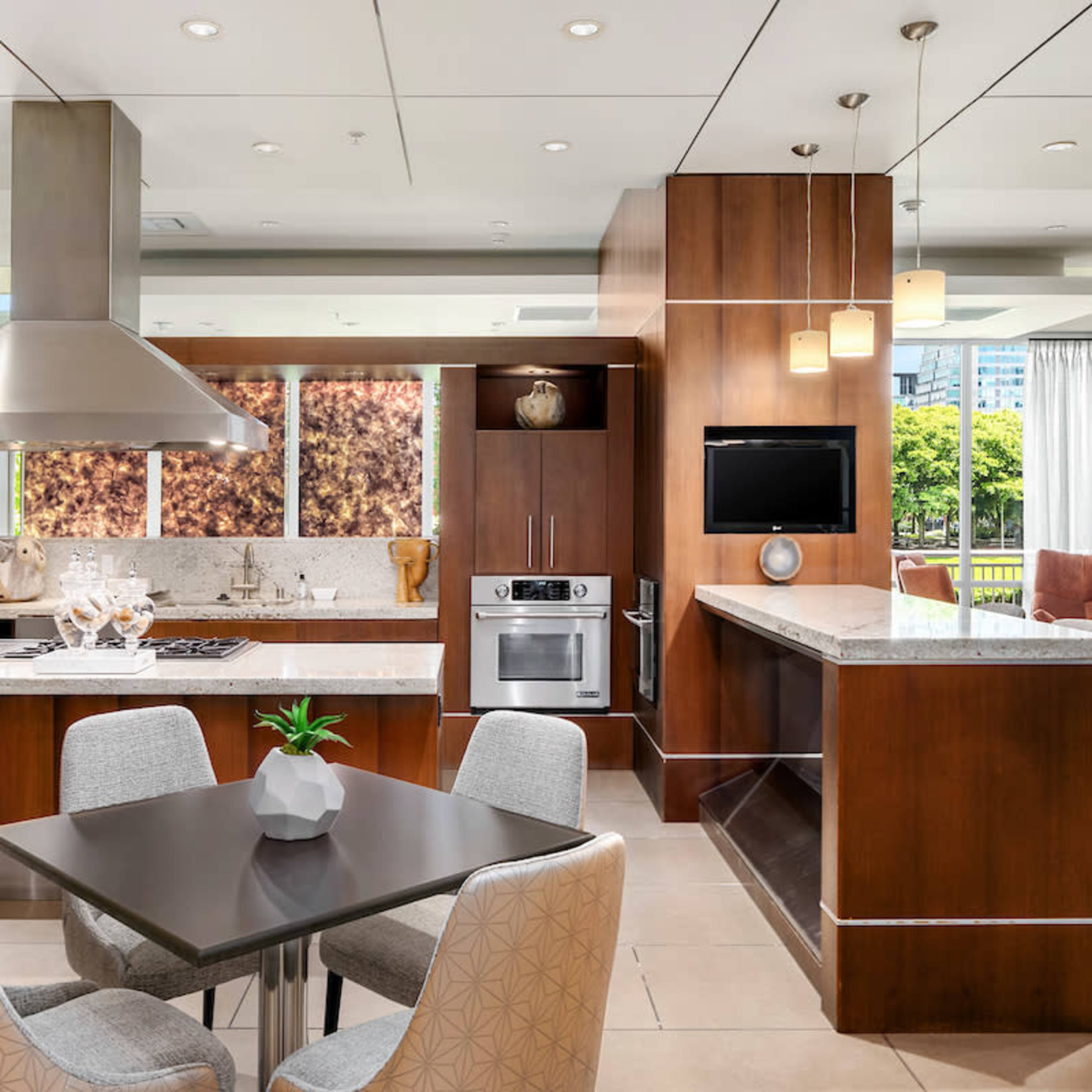 A modern kitchen features dark wood cabinetry, a large island with a silver exhaust hood, and stainless steel appliances.