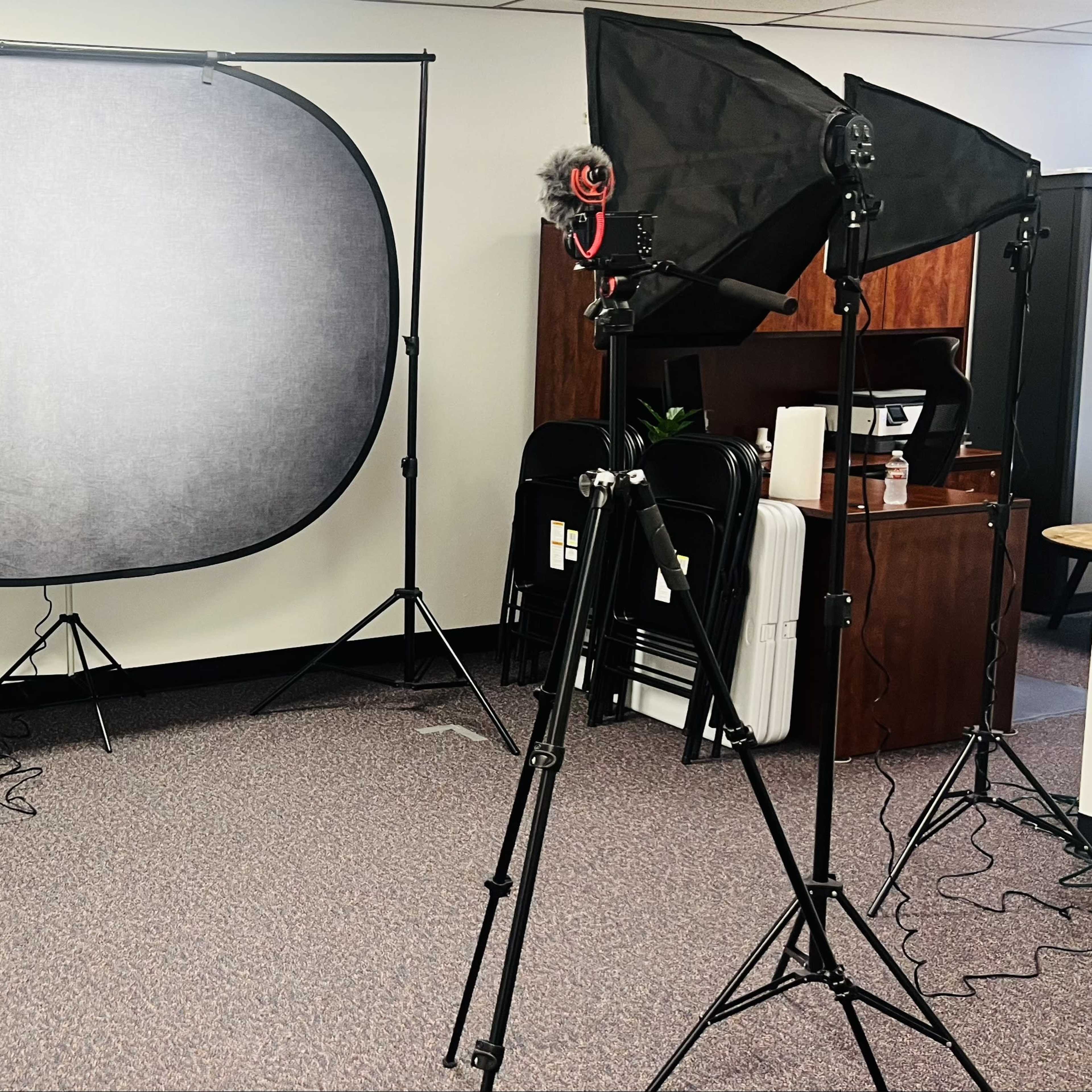 A photography setup featuring a backdrop, two softbox lights, and tripods in an indoor space.