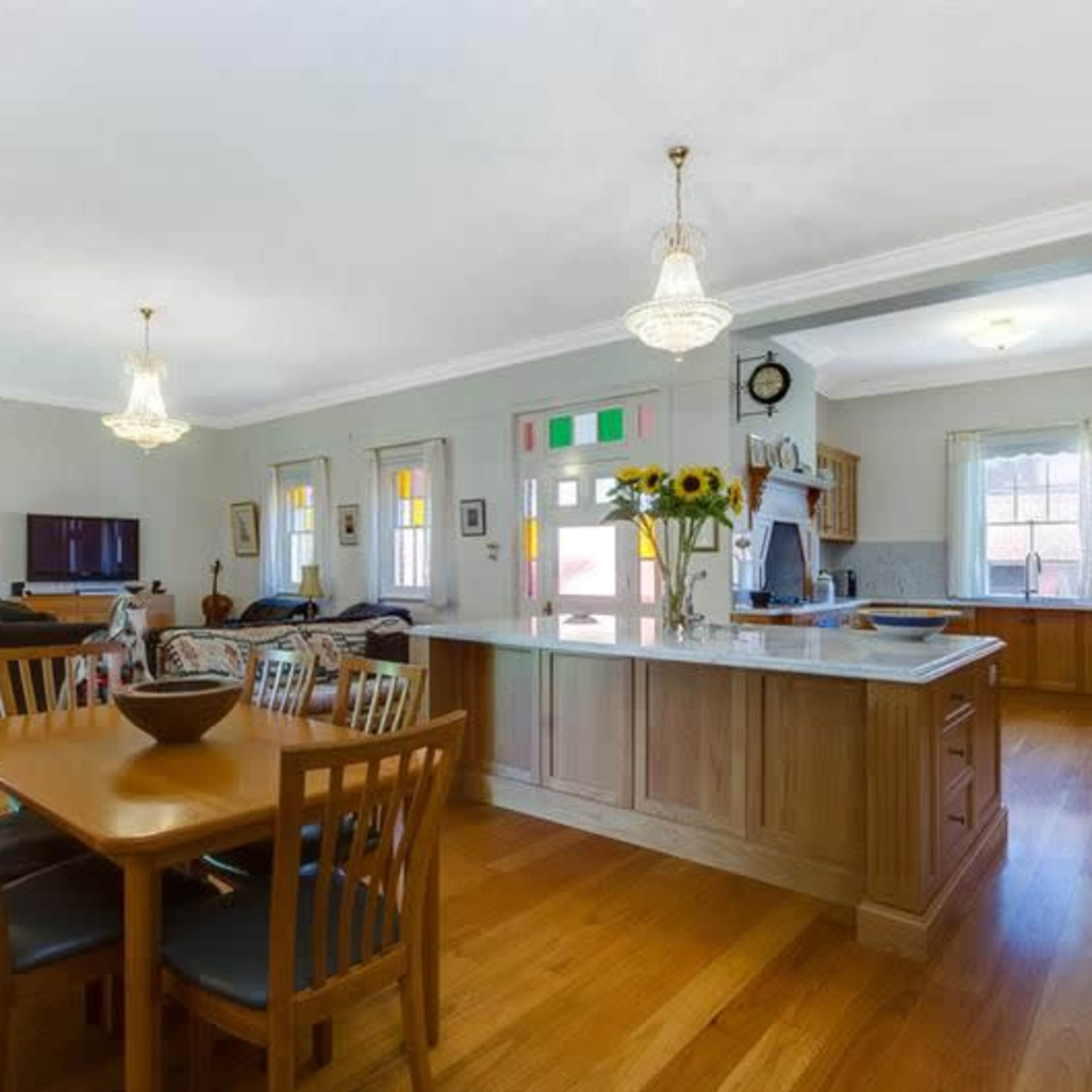 A spacious open-concept kitchen and dining area, featuring wooden floors, a large dining table, and a kitchen island.