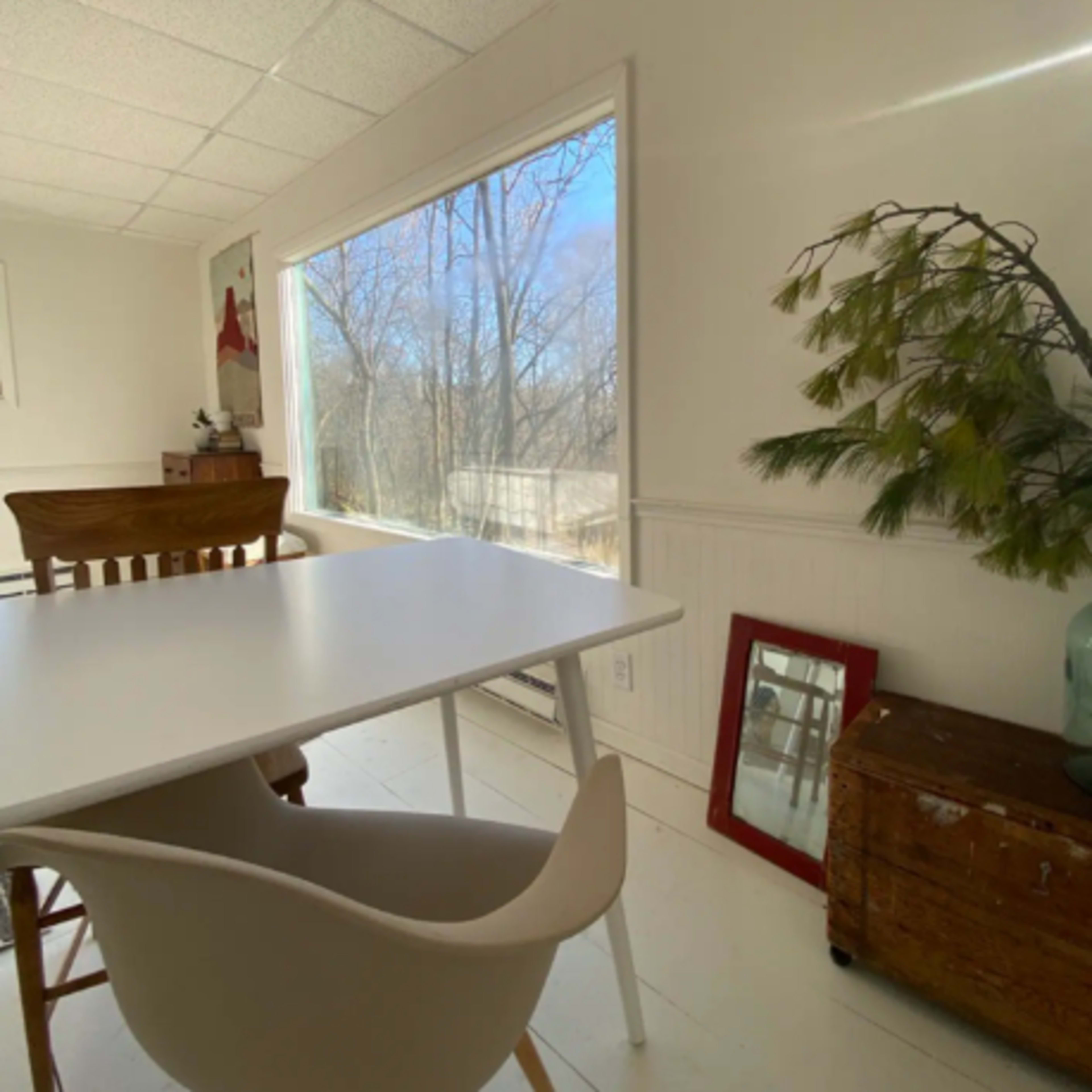 A bright dining area features a table and chair set next to a large window overlooking a natural landscape.