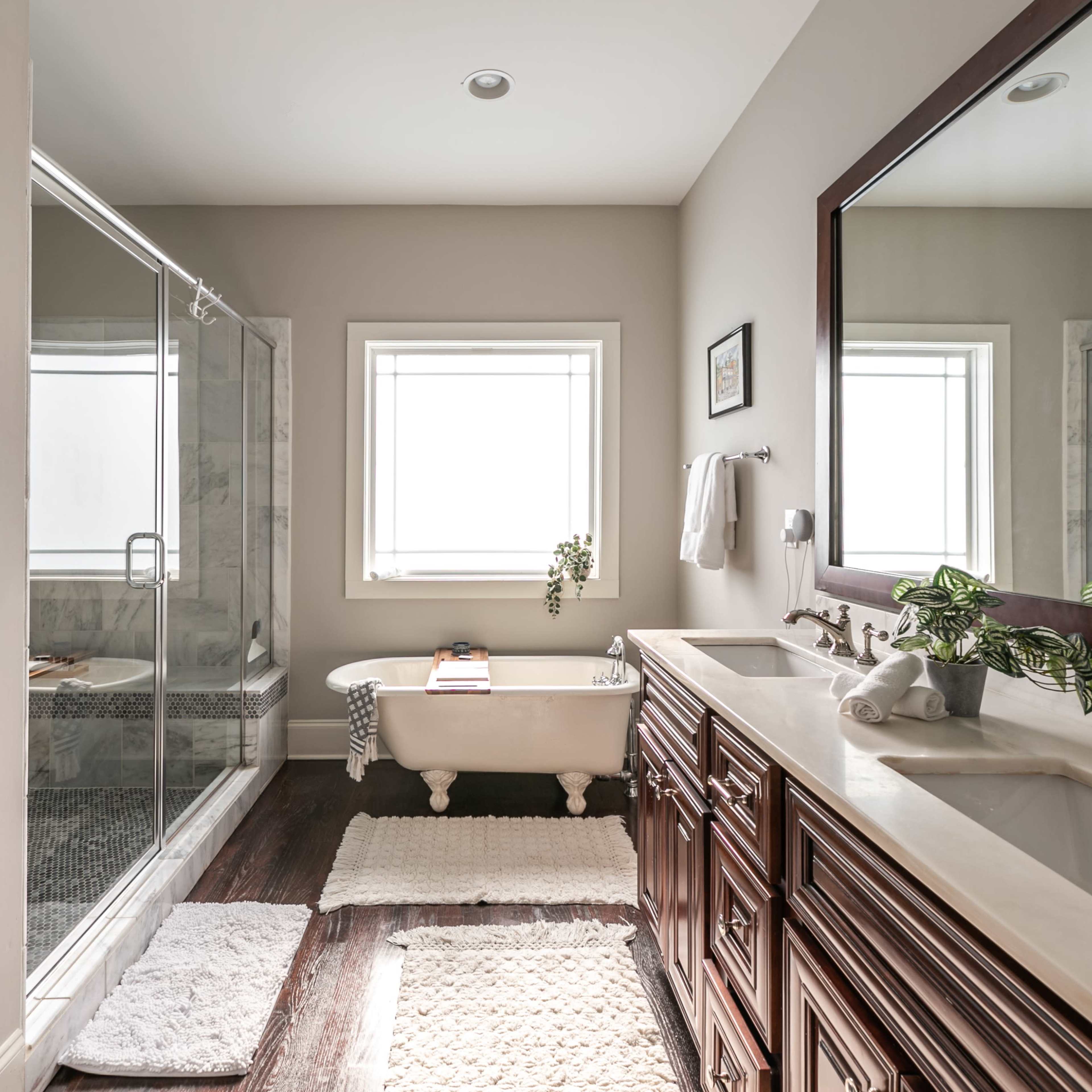 A spacious bathroom featuring a freestanding bathtub, a glass shower enclosure, and a double sink vanity with dark wood cabinetry.