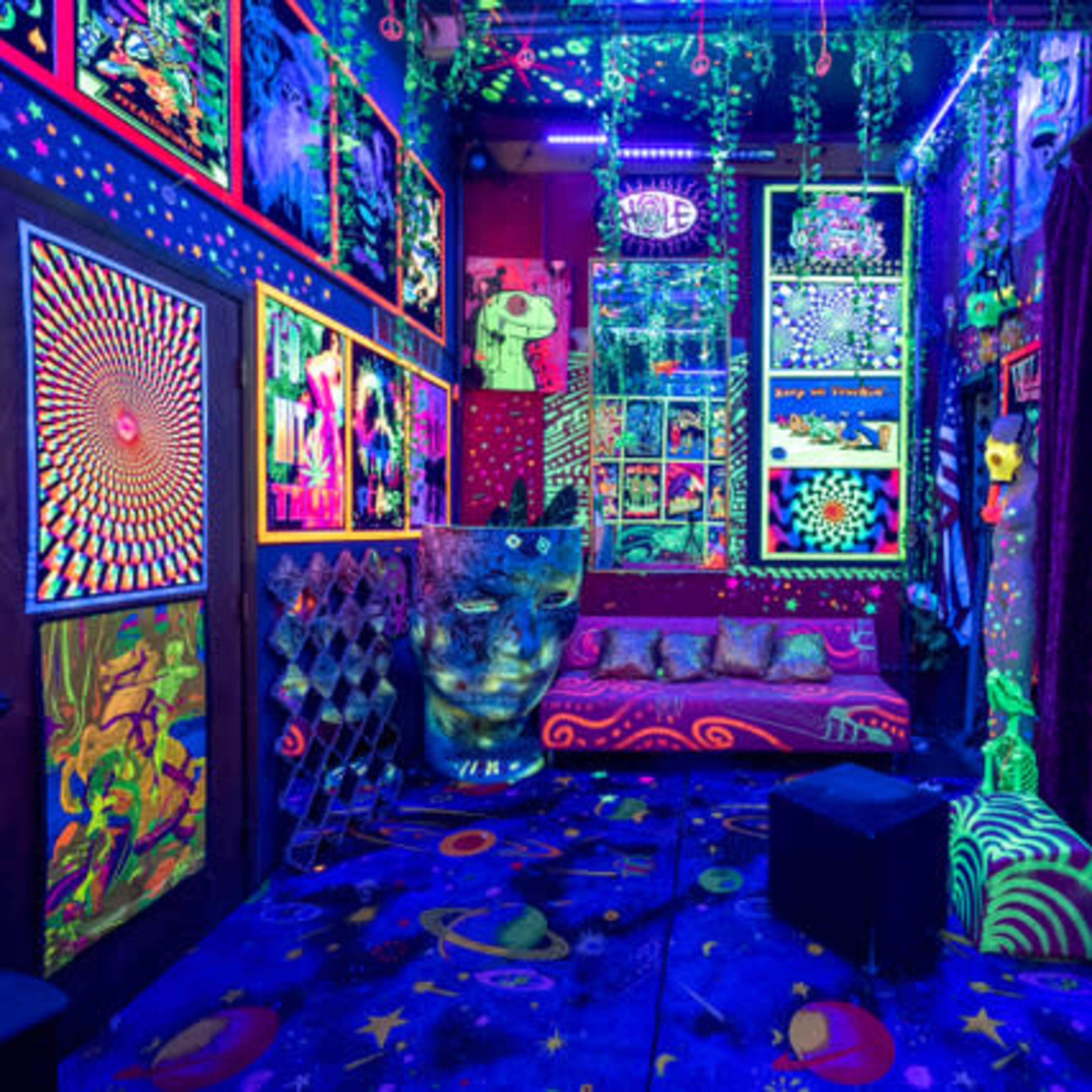 The room features vibrant glow-in-the-dark artwork on the walls, colorful decorations, and a patterned floor under black light.