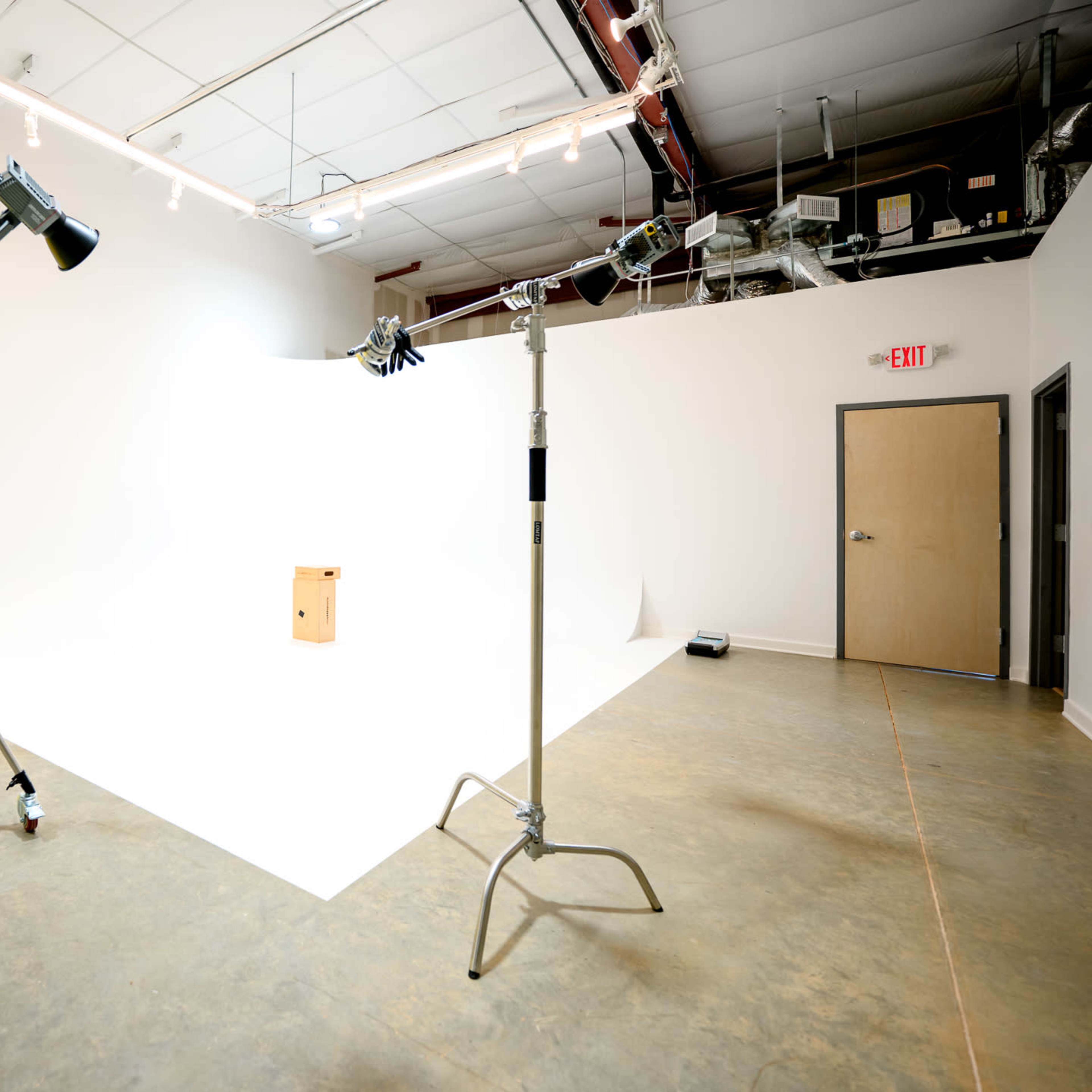 A photography studio with two lighting setups and a yellow backdrop, featuring a small wooden box placed on a white backdrop.