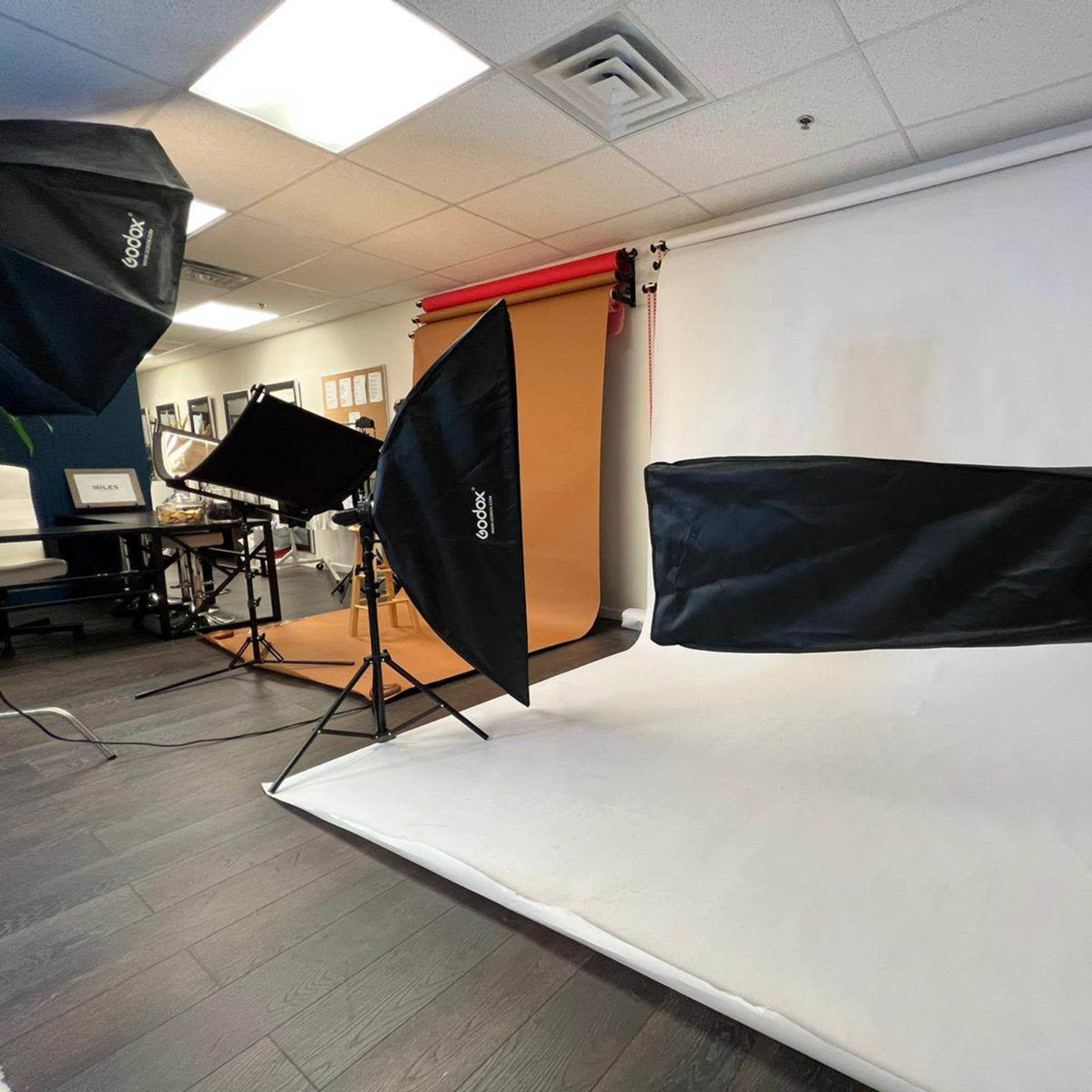 A photography studio setup with various background colors and lighting equipment arranged around a main shooting area.