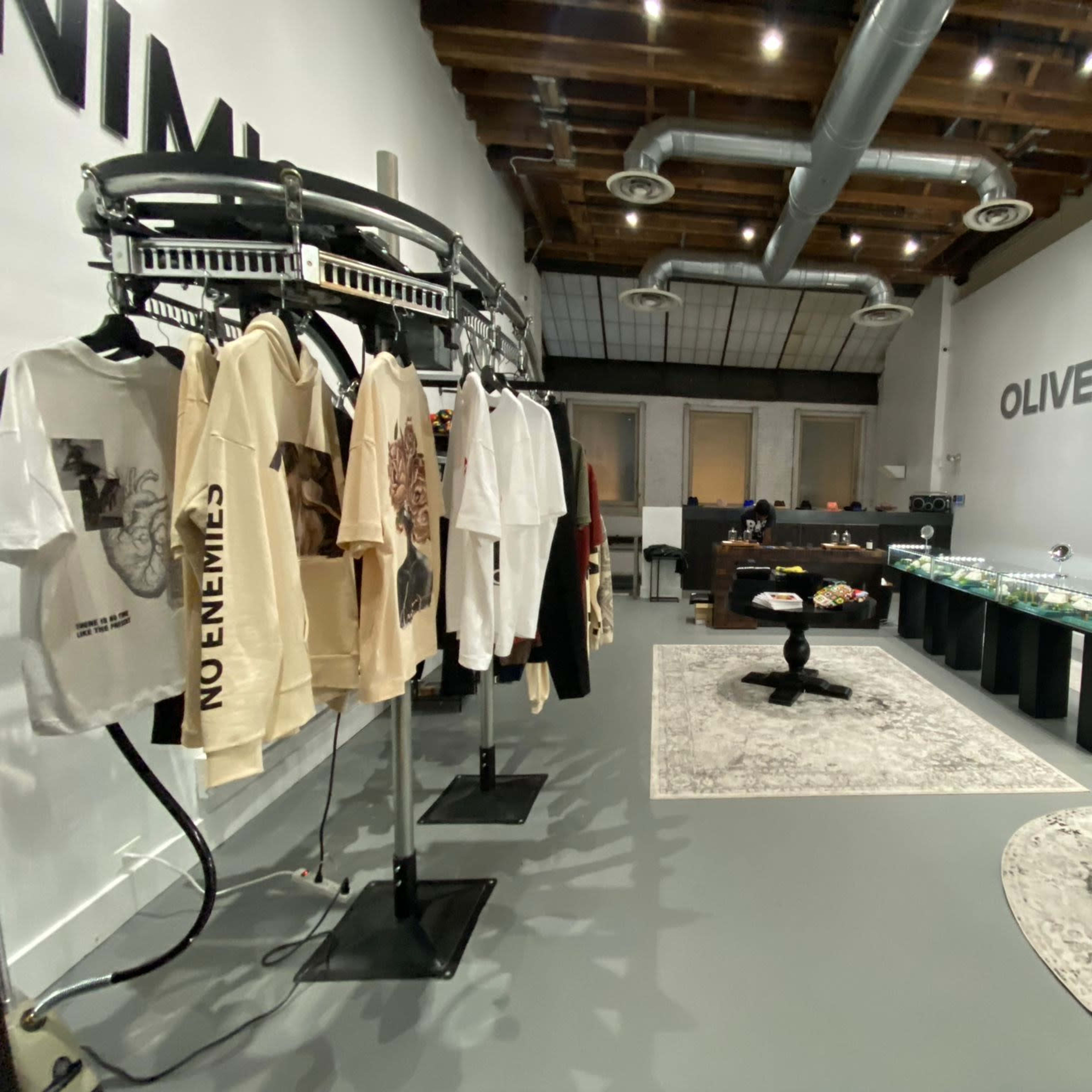 A boutique interior featuring clothing racks, a display case with jewelry, and a lounge area with a round table and plush seating.